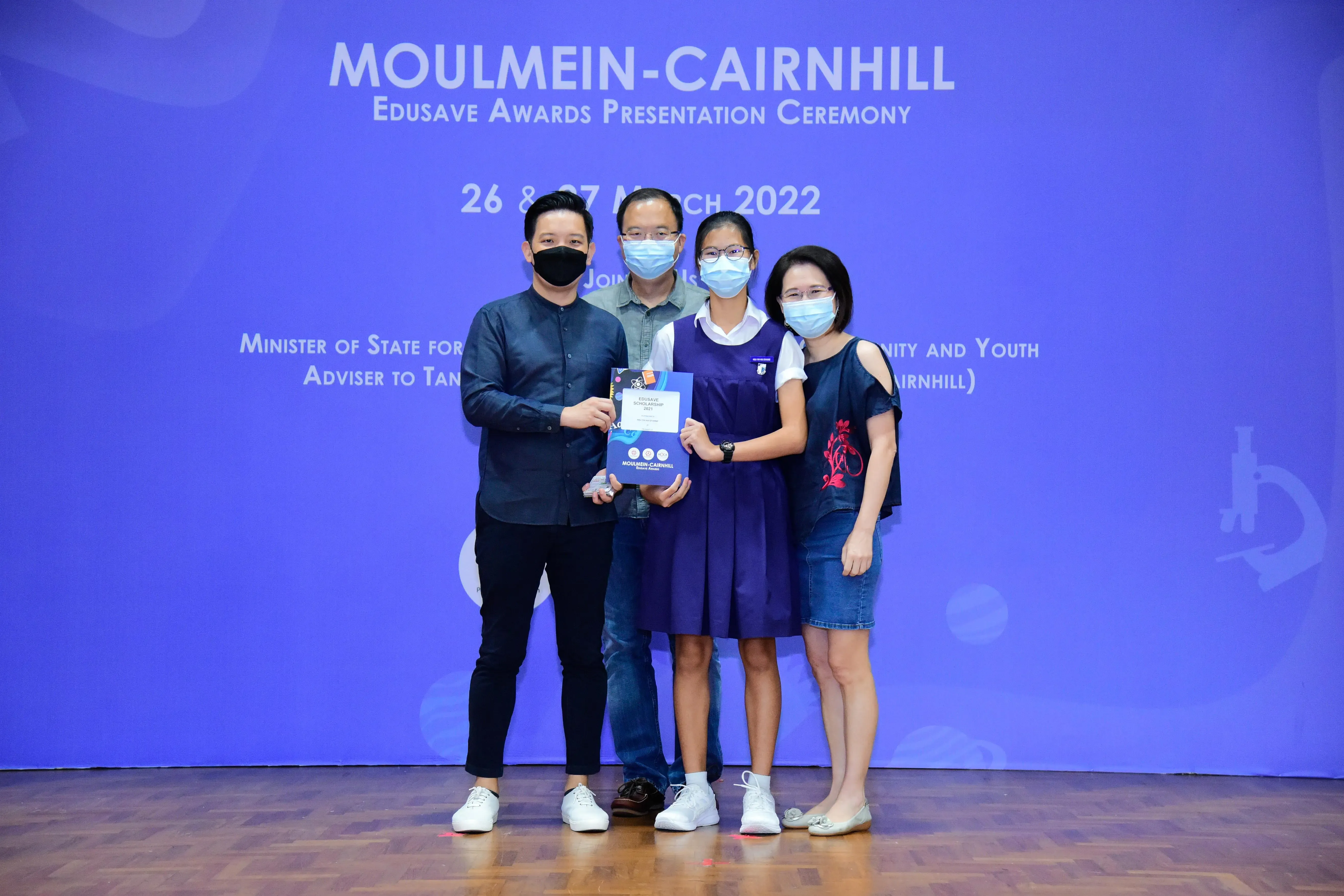 Four masked people pose together at the Moulmein-Cairnhill Edusave Awards Presentation Ceremony on 26-27 March 2022.