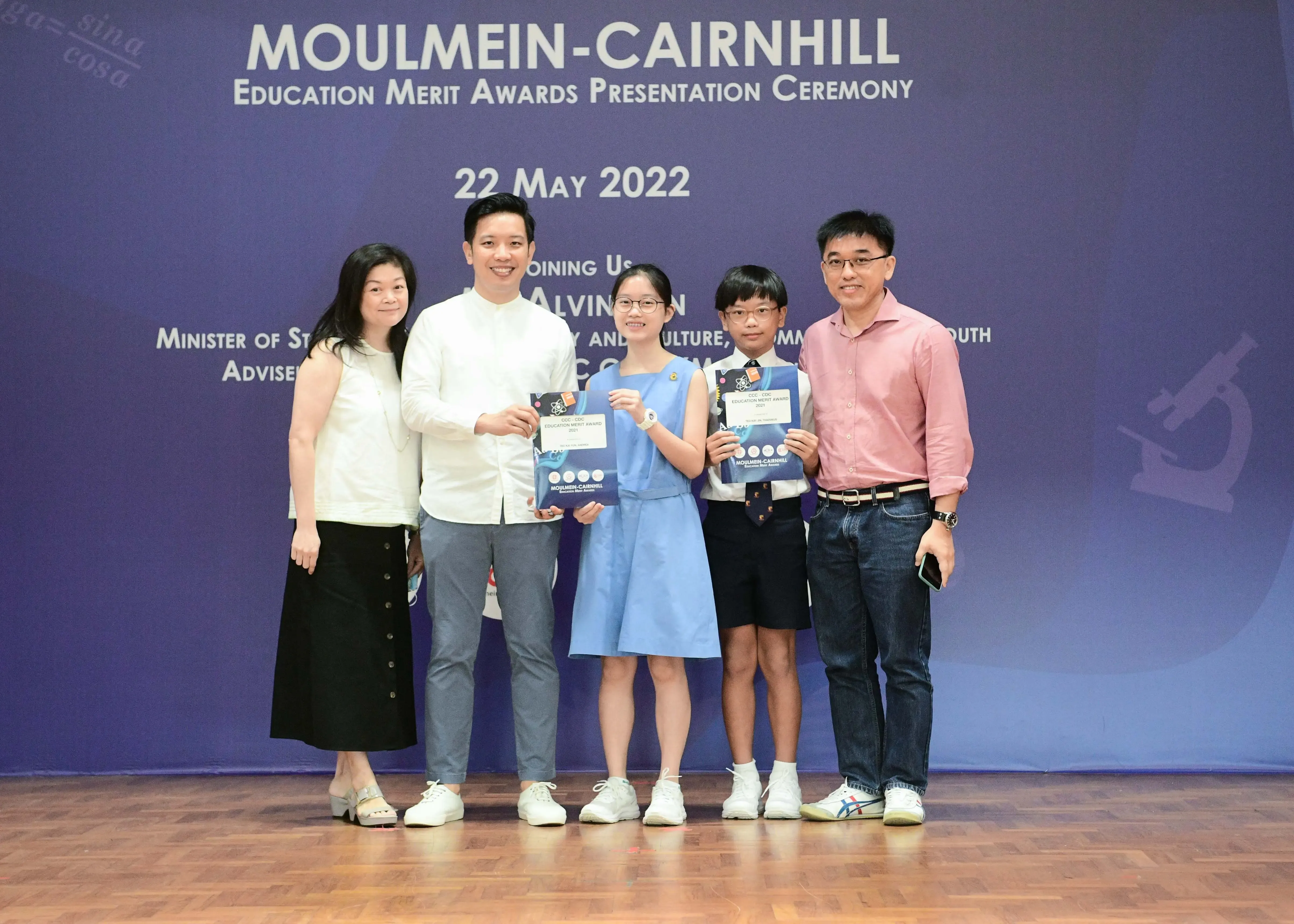Five people pose with award booklets at the Moulmein-Cairnhill Education Merit Awards Presentation Ceremony on 22 May 2022.