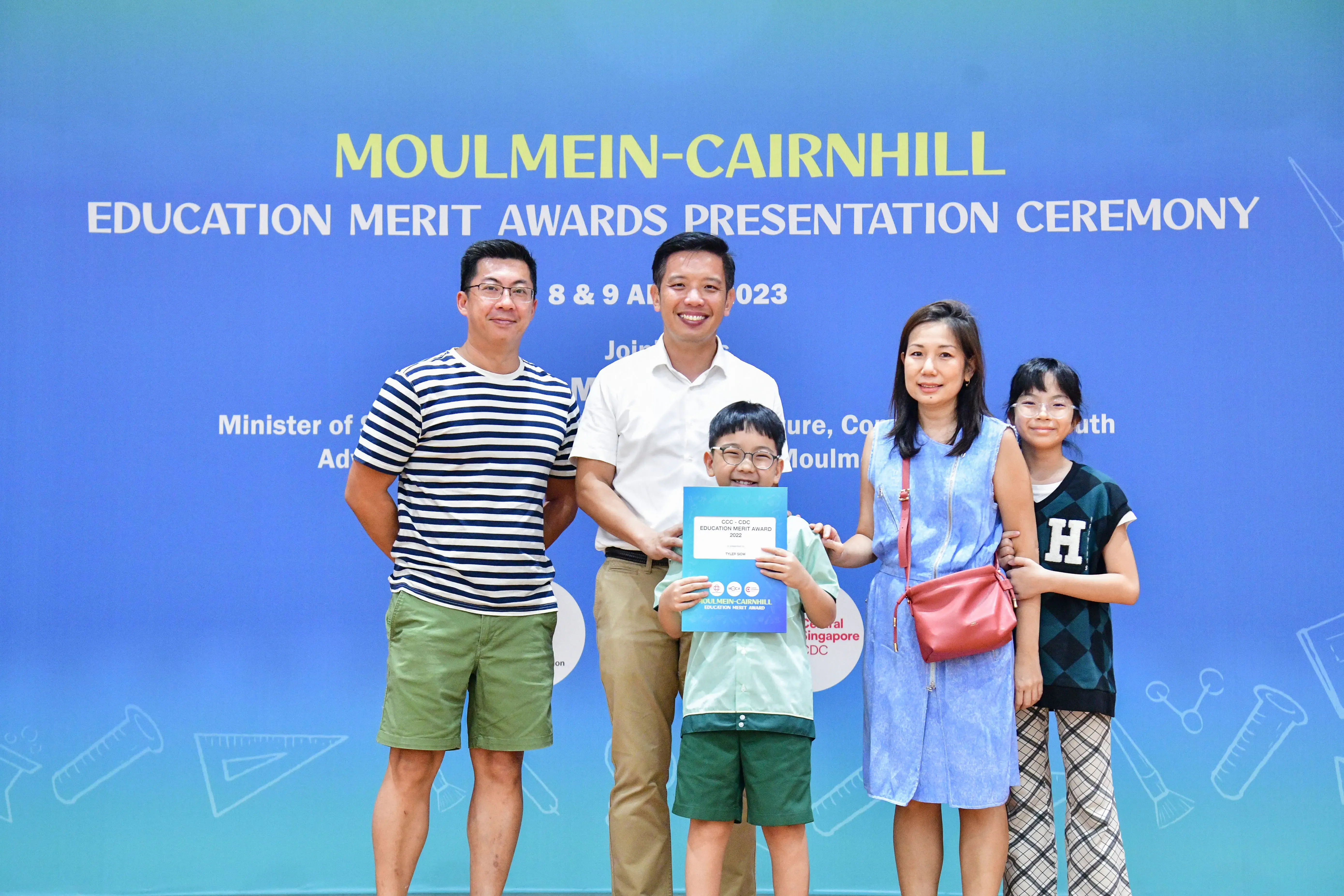 Four adults and two children pose at the Moulmein-Cairnhill Education Merit Awards Presentation Ceremony 2023.