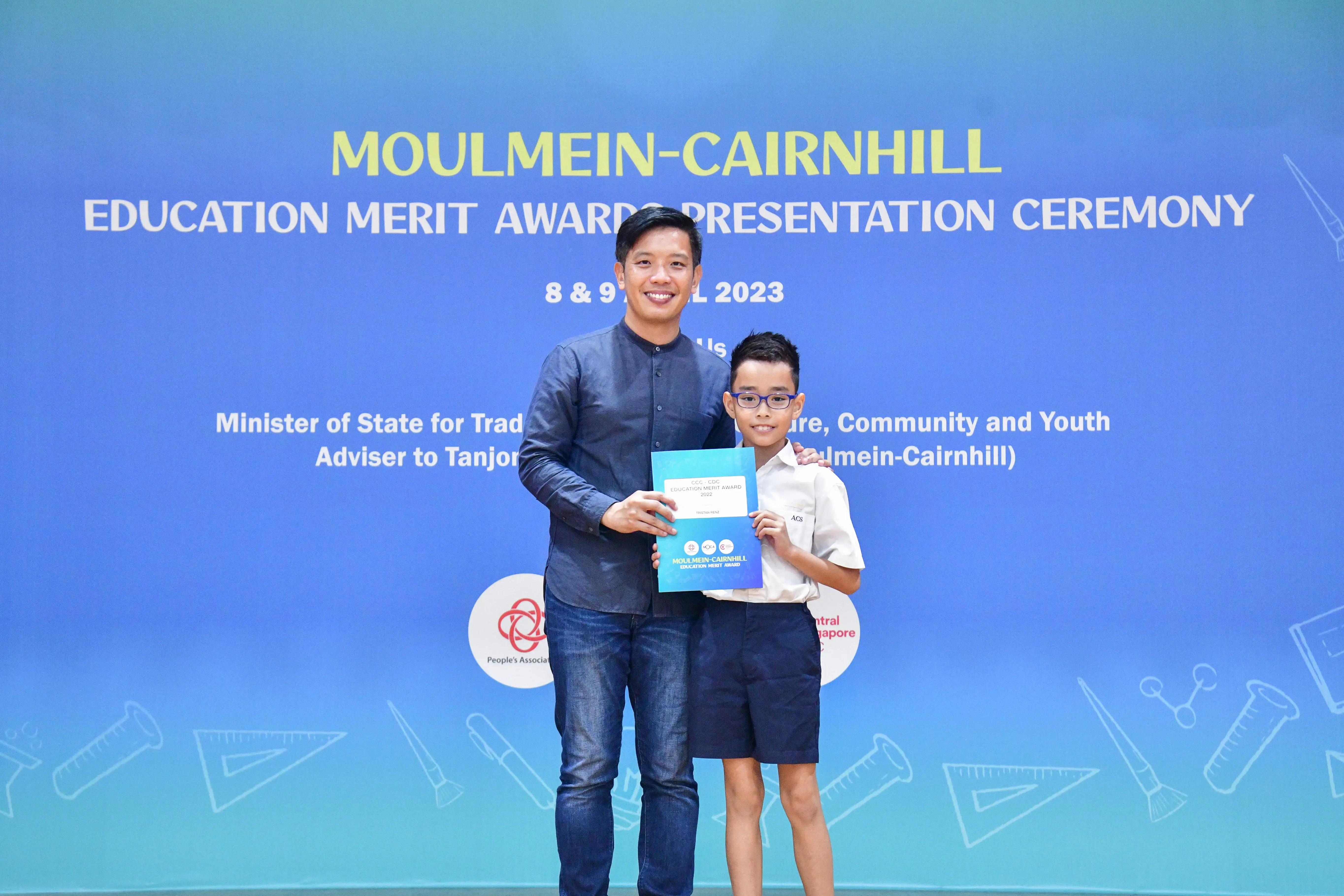 A man and a young boy holding an award certificate at the Moulmein-Cairnhill Education Merit Awards 2023.