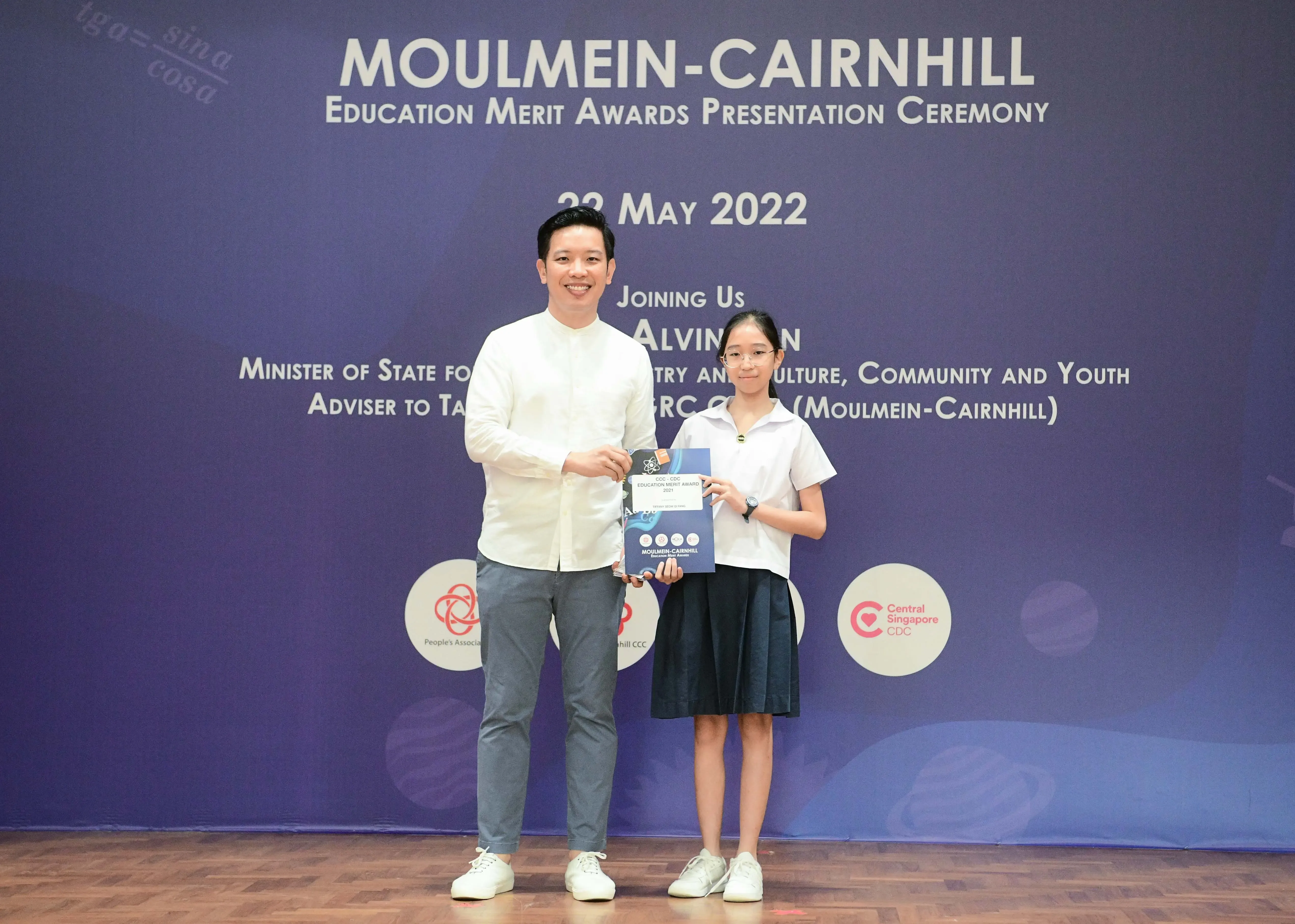A man and a young girl hold an award certificate at the Moulmein-Cairnhill Education Merit Awards ceremony on 22 May 2022.
