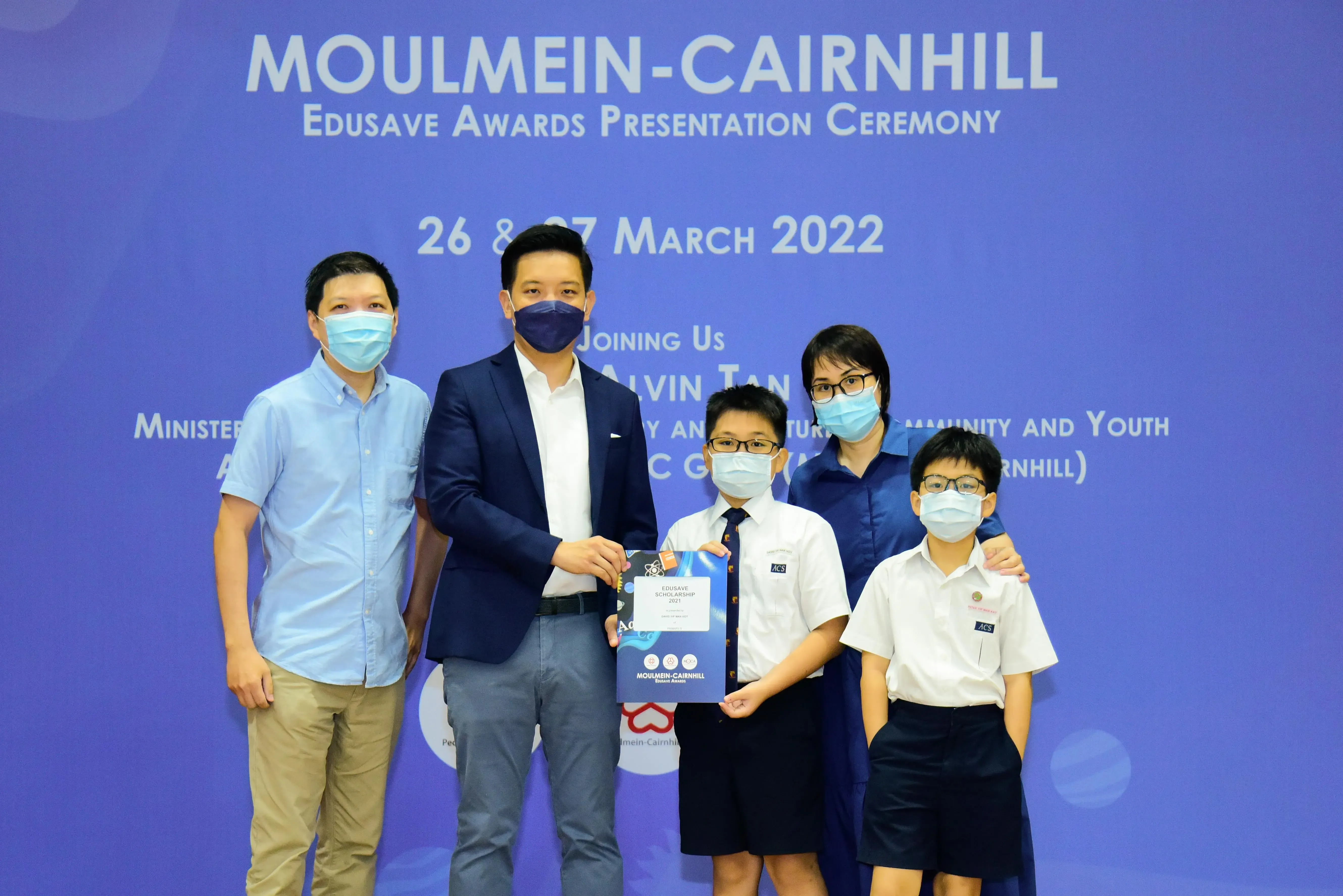Five masked people pose at the Moulmein-Cairnhill Edusave Awards Presentation Ceremony on 26-27 March 2022.