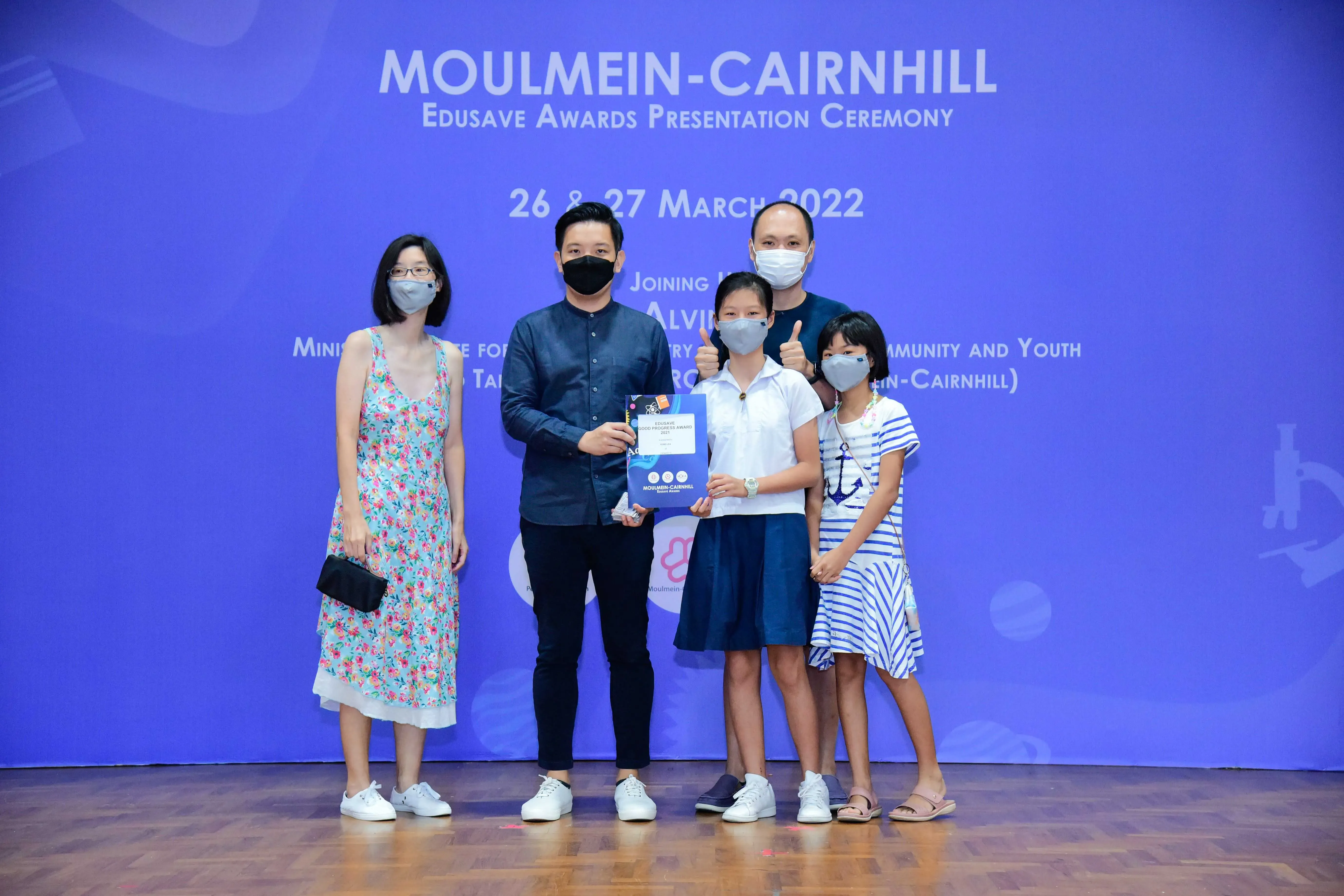 Five masked people pose with a certificate at the Moulmein-Cairnhill Edusave Awards Ceremony, March 2022.