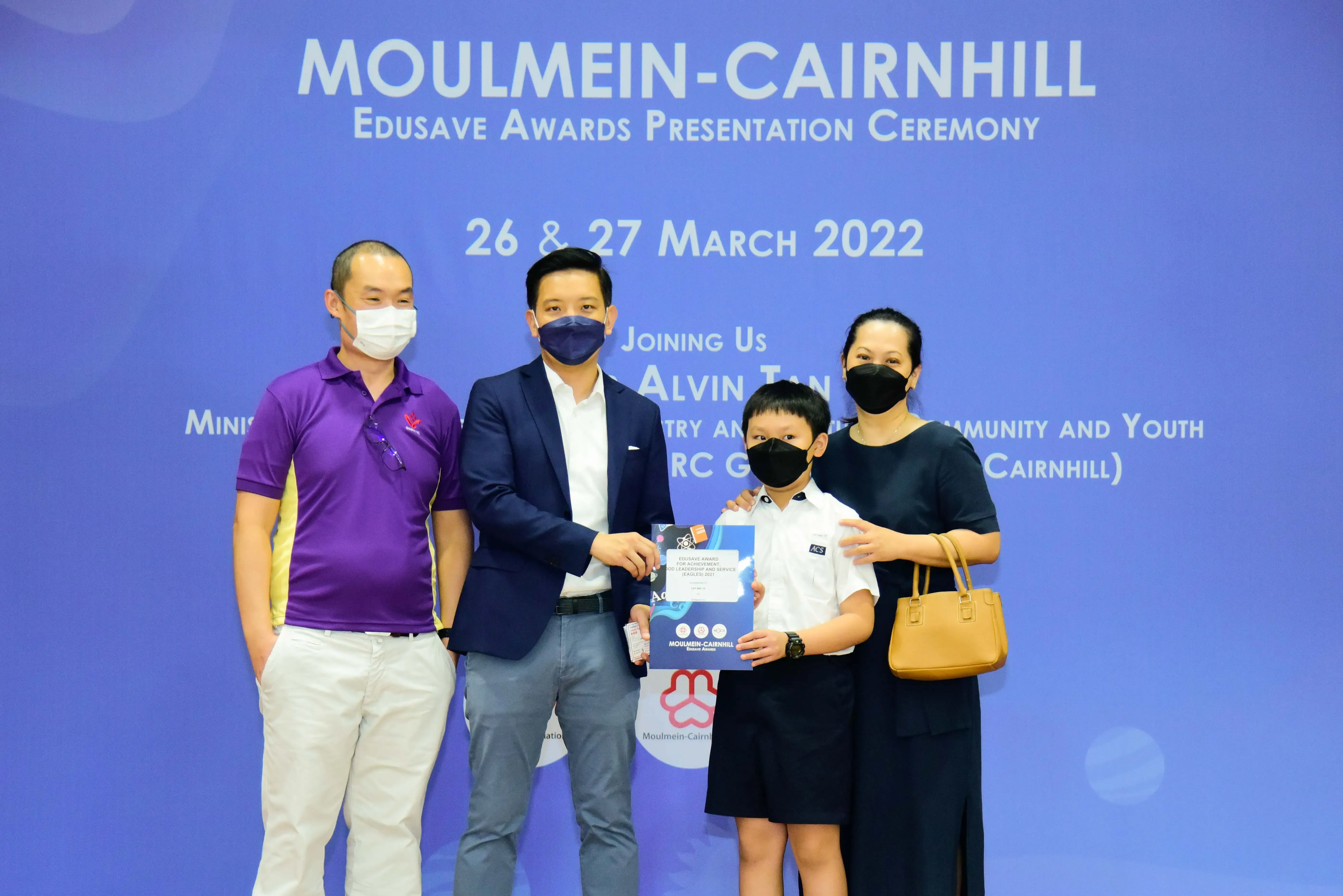 Four masked people pose at the Moulmein-Cairnhill Edusave Awards Presentation Ceremony on 26-27 March 2022.
