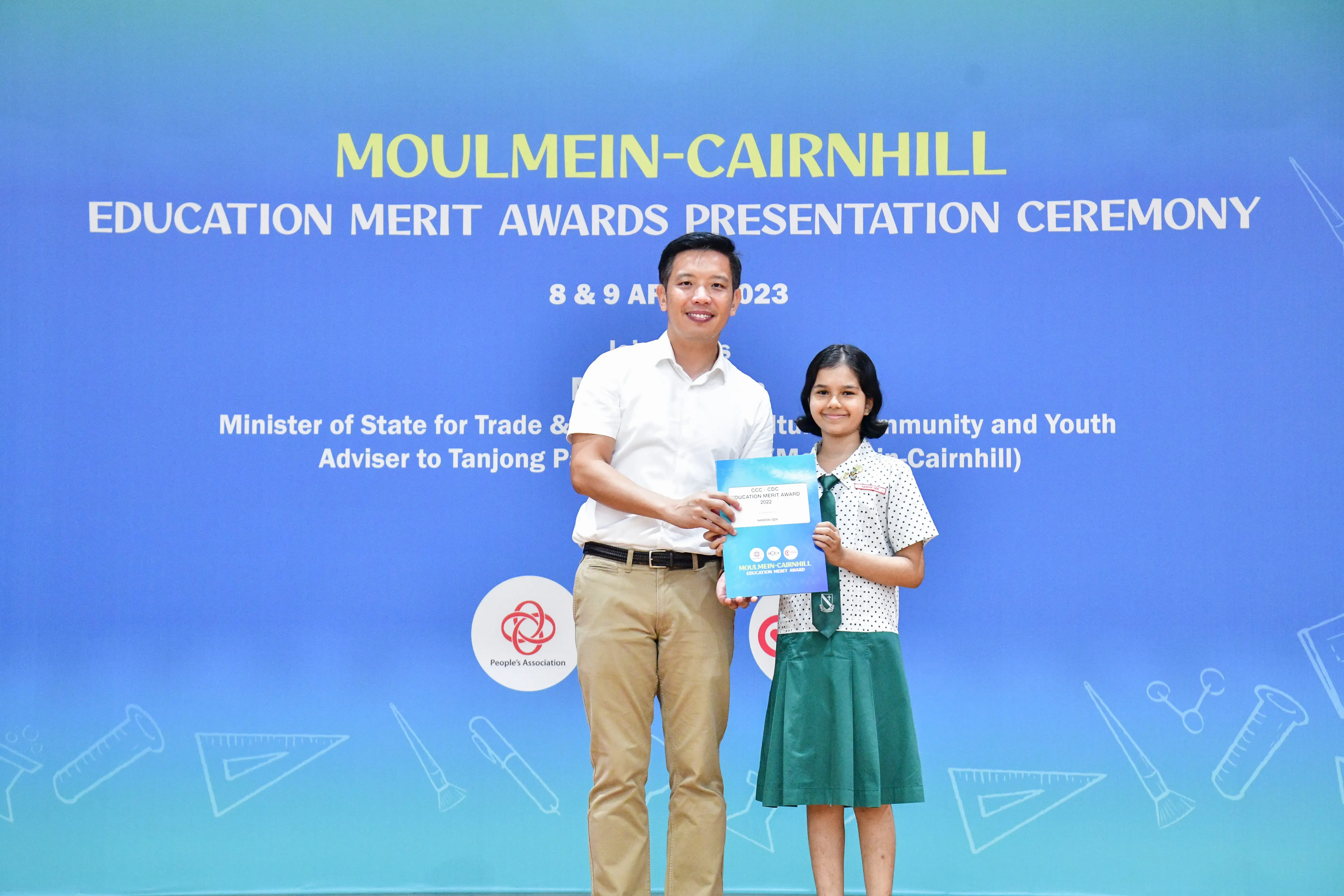 A man and a young girl in school uniform hold an award certificate at the Moulmein-Cairnhill Education Merit Awards 2023.