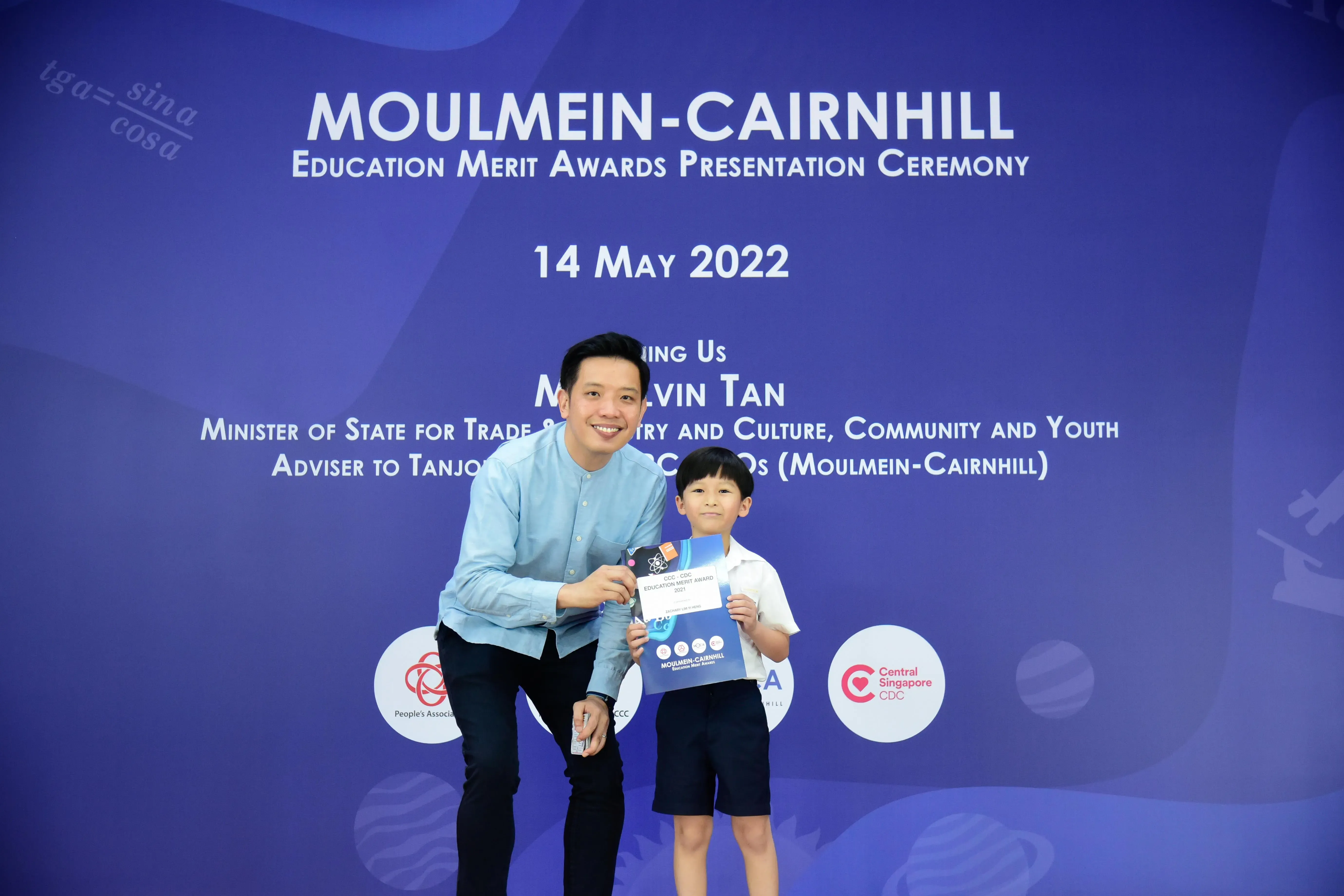 A man and a young boy pose holding an award at the Moulmein-Cairnhill Education Merit Awards ceremony on 14 May 2022.