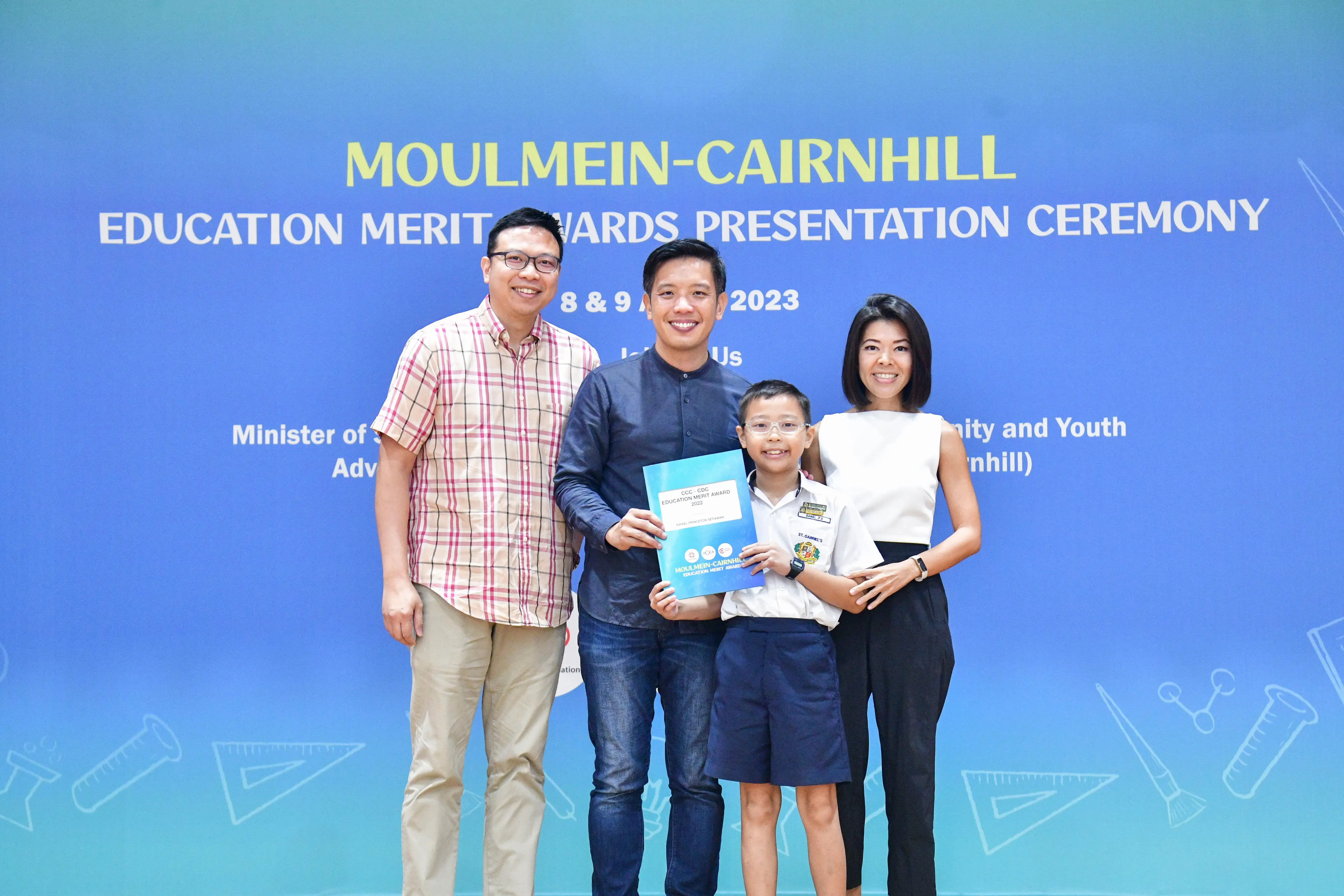 Three adults and a young boy pose with an award certificate at the Moulmein-Cairnhill Education Merit Awards 2023.