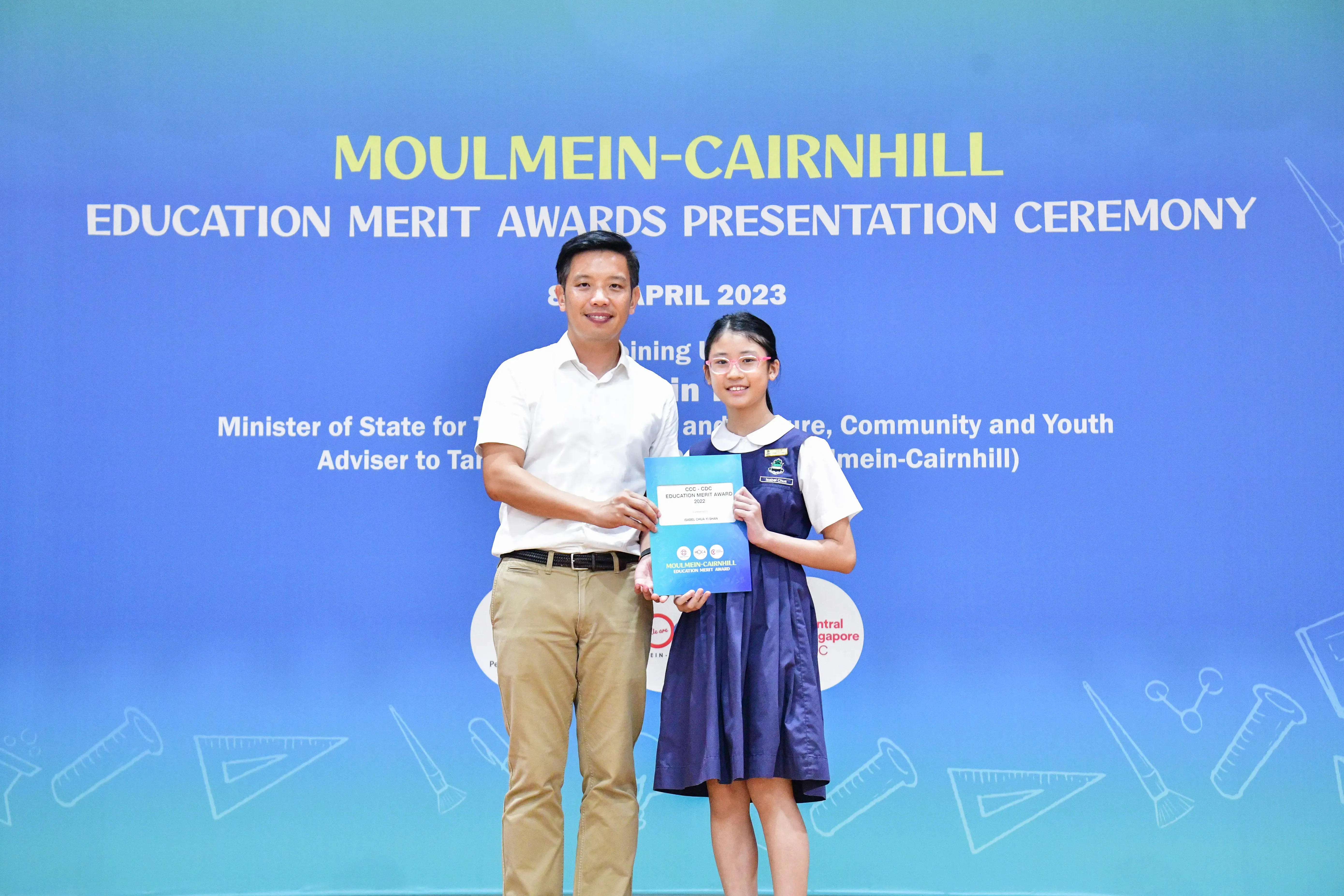 A man and a young girl in school uniform hold a certificate at the Moulmein-Cairnhill Education Merit Awards 2023.