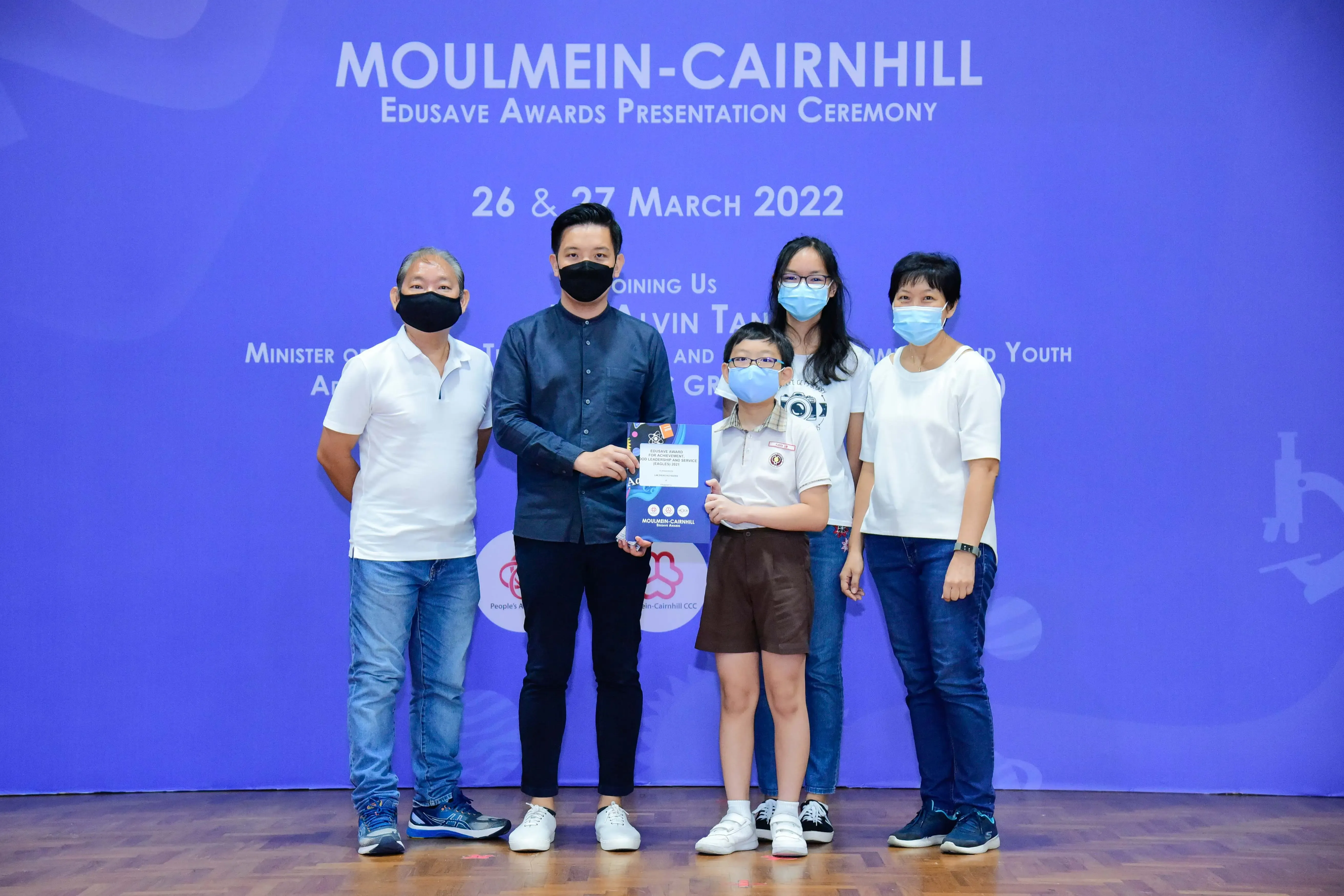Five masked people pose at the Moulmein-Cairnhill Edusave Awards Presentation Ceremony on 26-27 March 2022.
