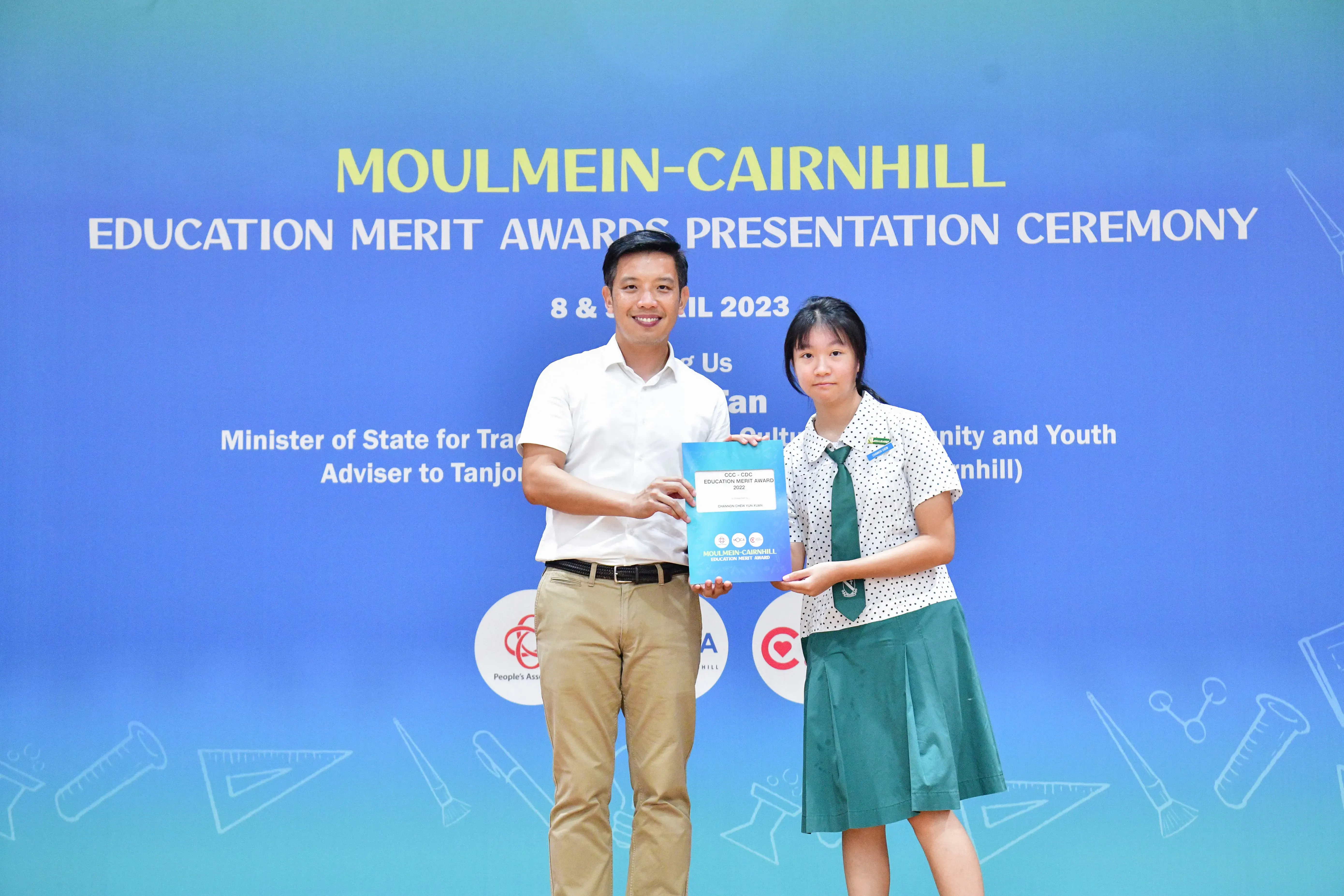 A man and a student in school uniform hold an award together at the Moulmein-Cairnhill Education Merit Awards 2023.
