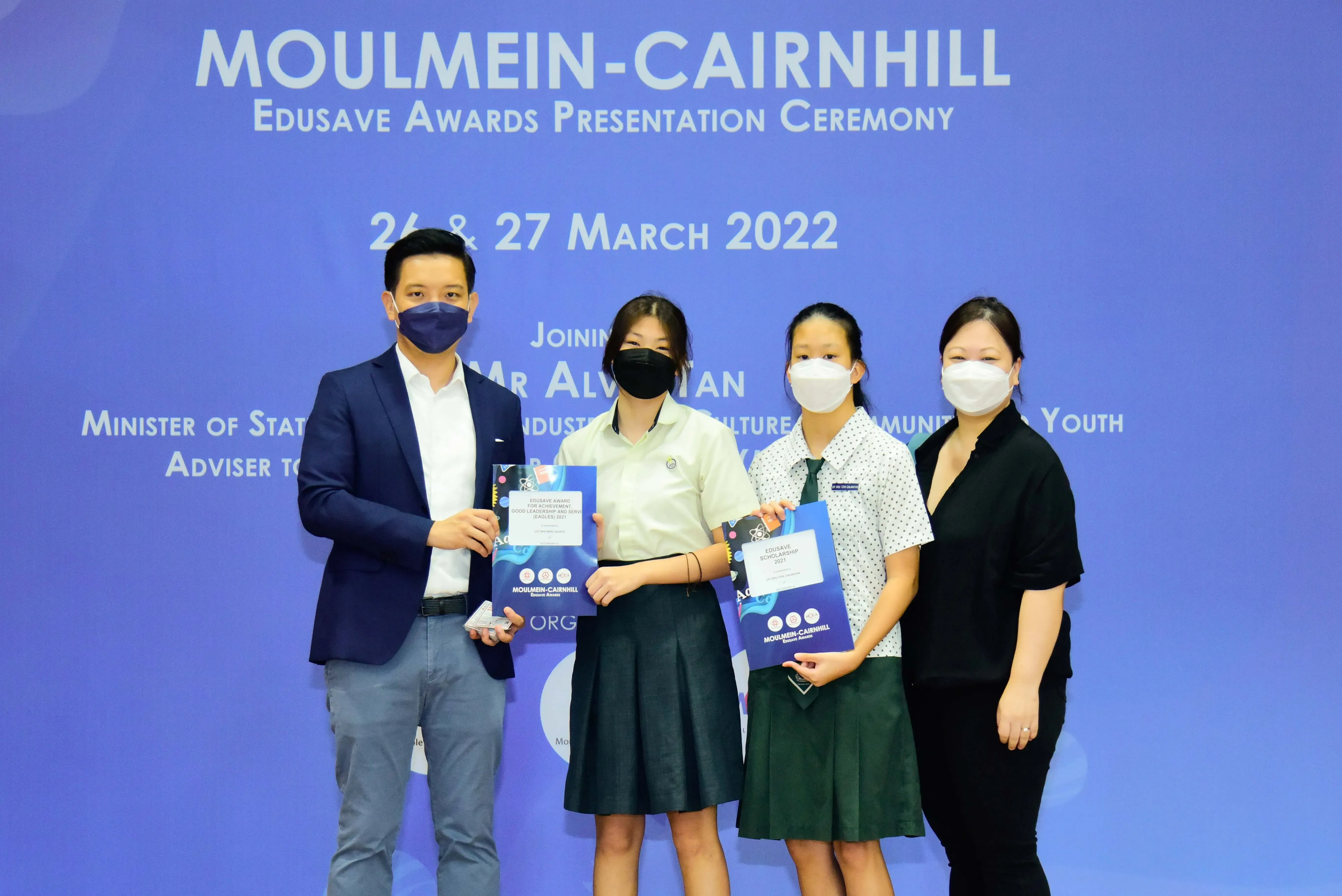 Four masked people pose at the Moulmein-Cairnhill Edusave Awards Presentation Ceremony on 26-27 March 2022.