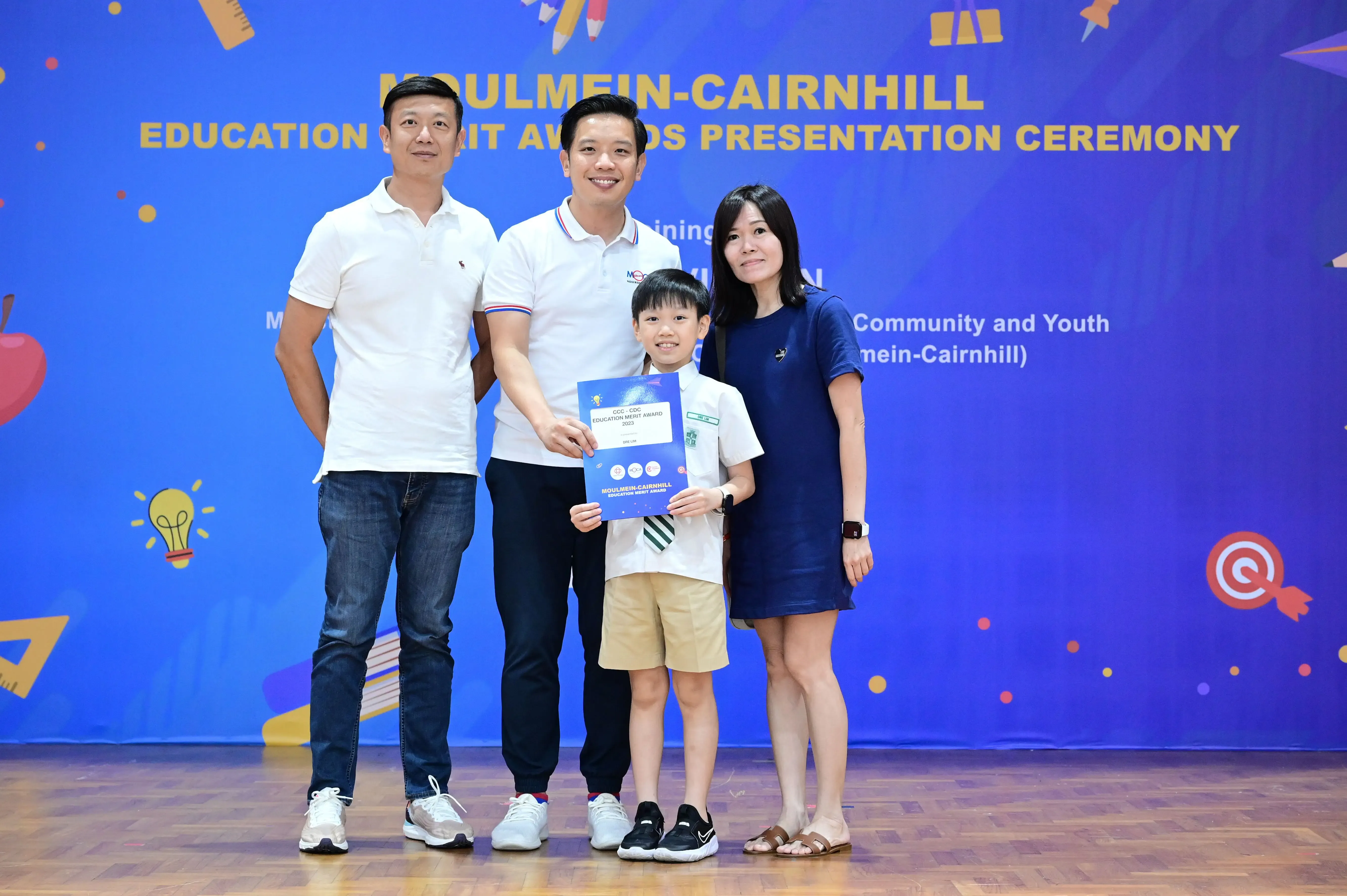 Three adults and a boy holding a certificate pose at the Moulmein-Cairnhill Education Merit Awards Ceremony.