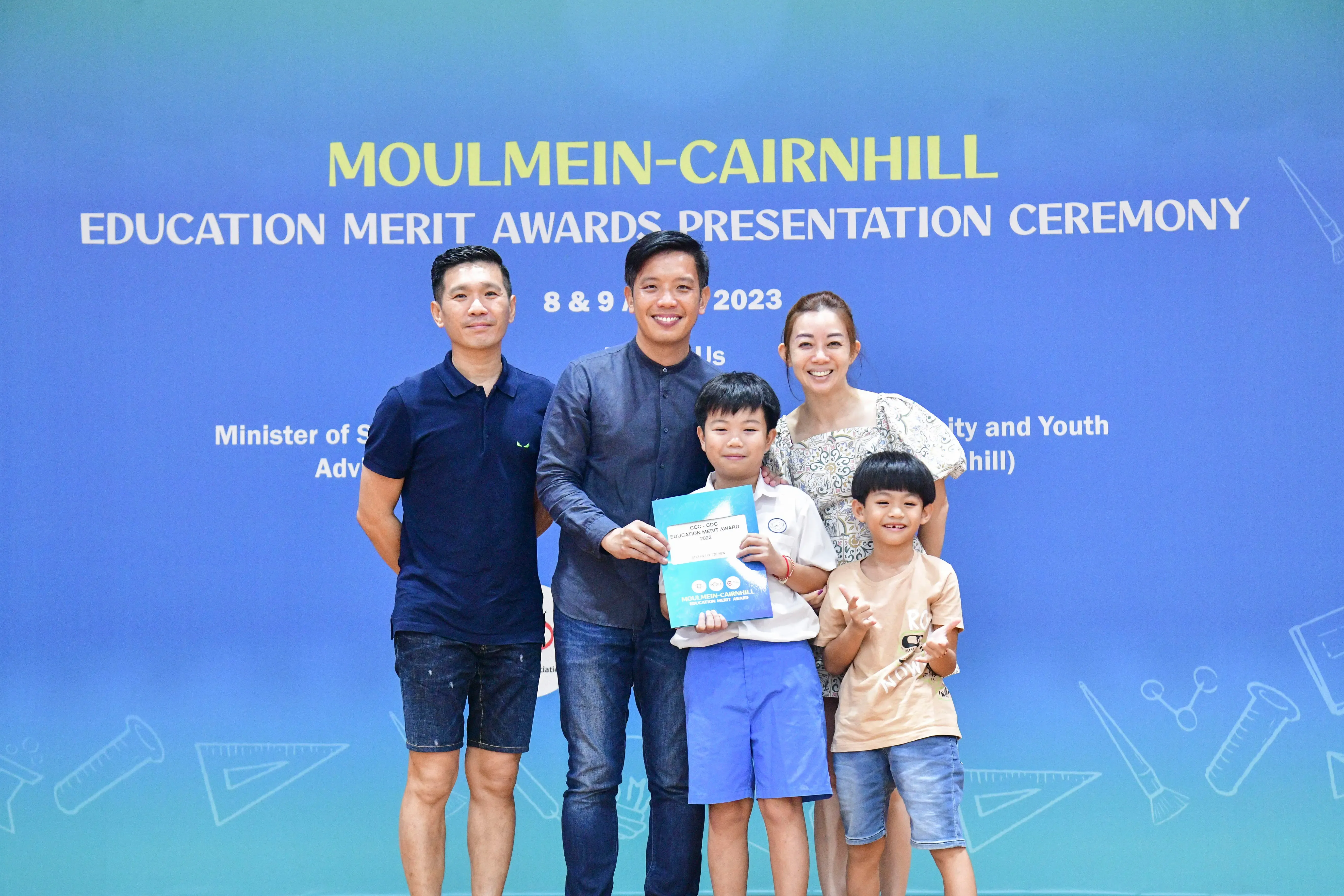 Two adults and two children pose with an award certificate at the Moulmein-Cairnhill Education Merit Awards 2023.