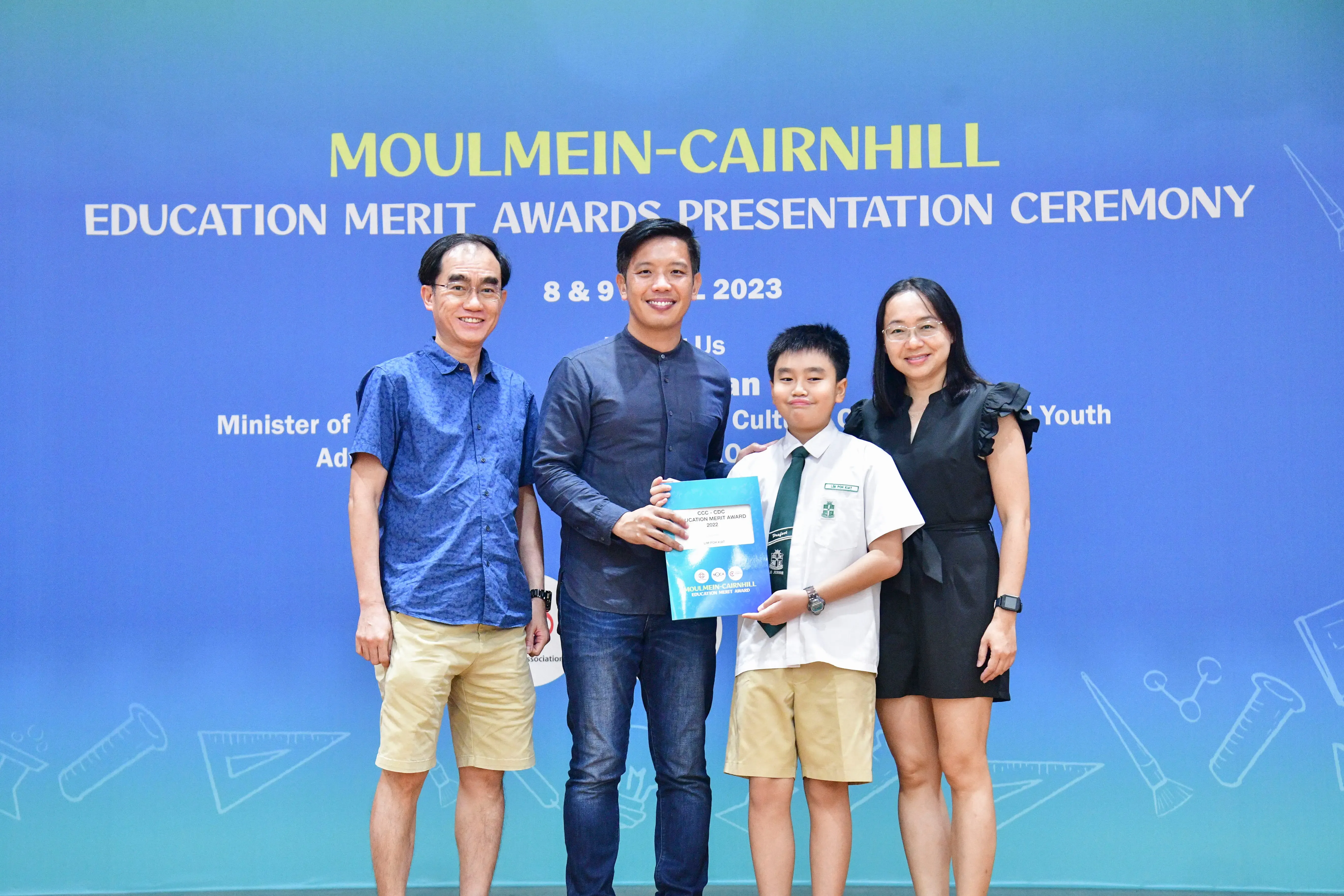 Three adults and a young student in school uniform pose at the Moulmein-Cairnhill Education Merit Awards 2023.