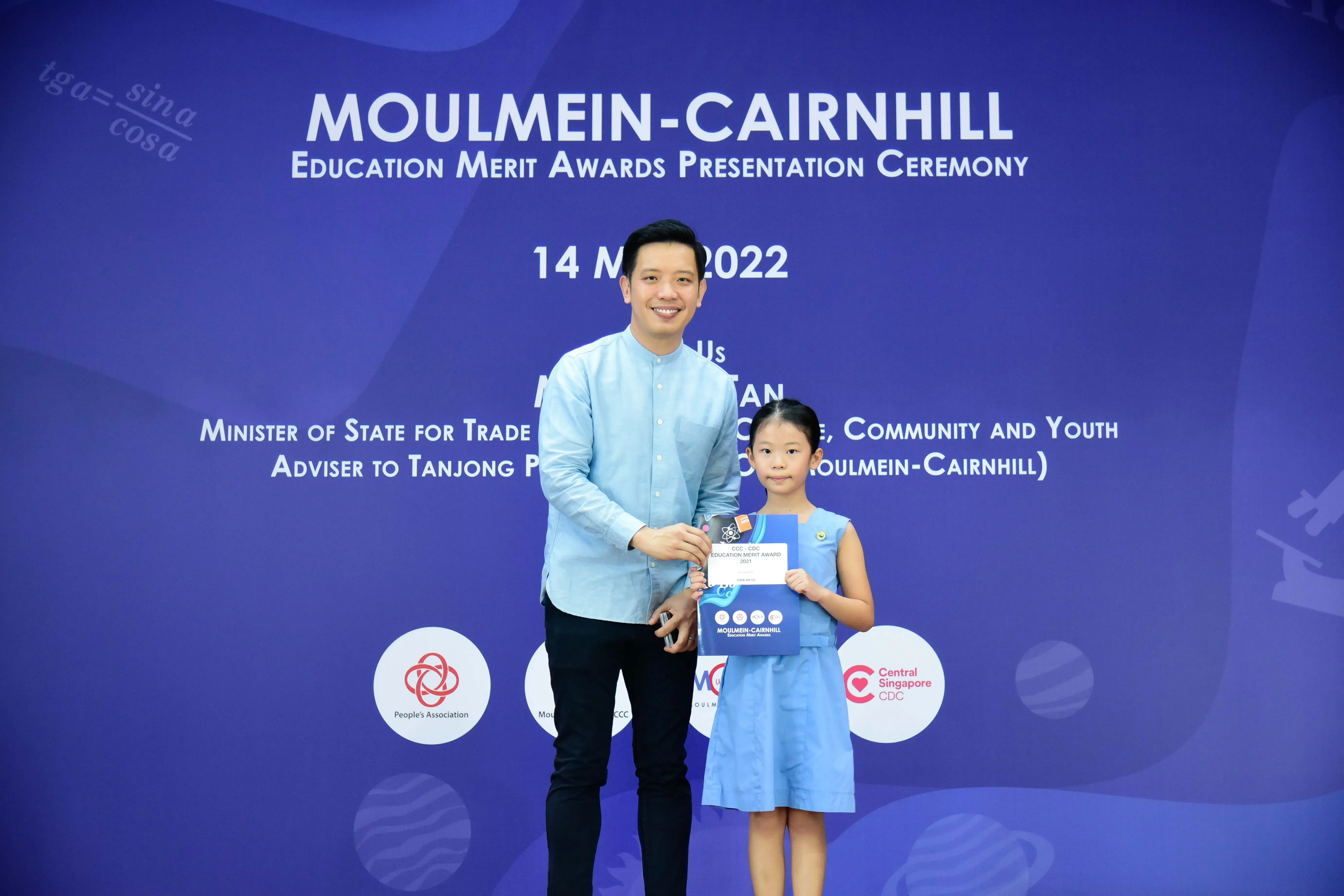 A man and a young girl pose together holding an award at the Moulmein-Cairnhill Education Merit Awards Ceremony 2022.