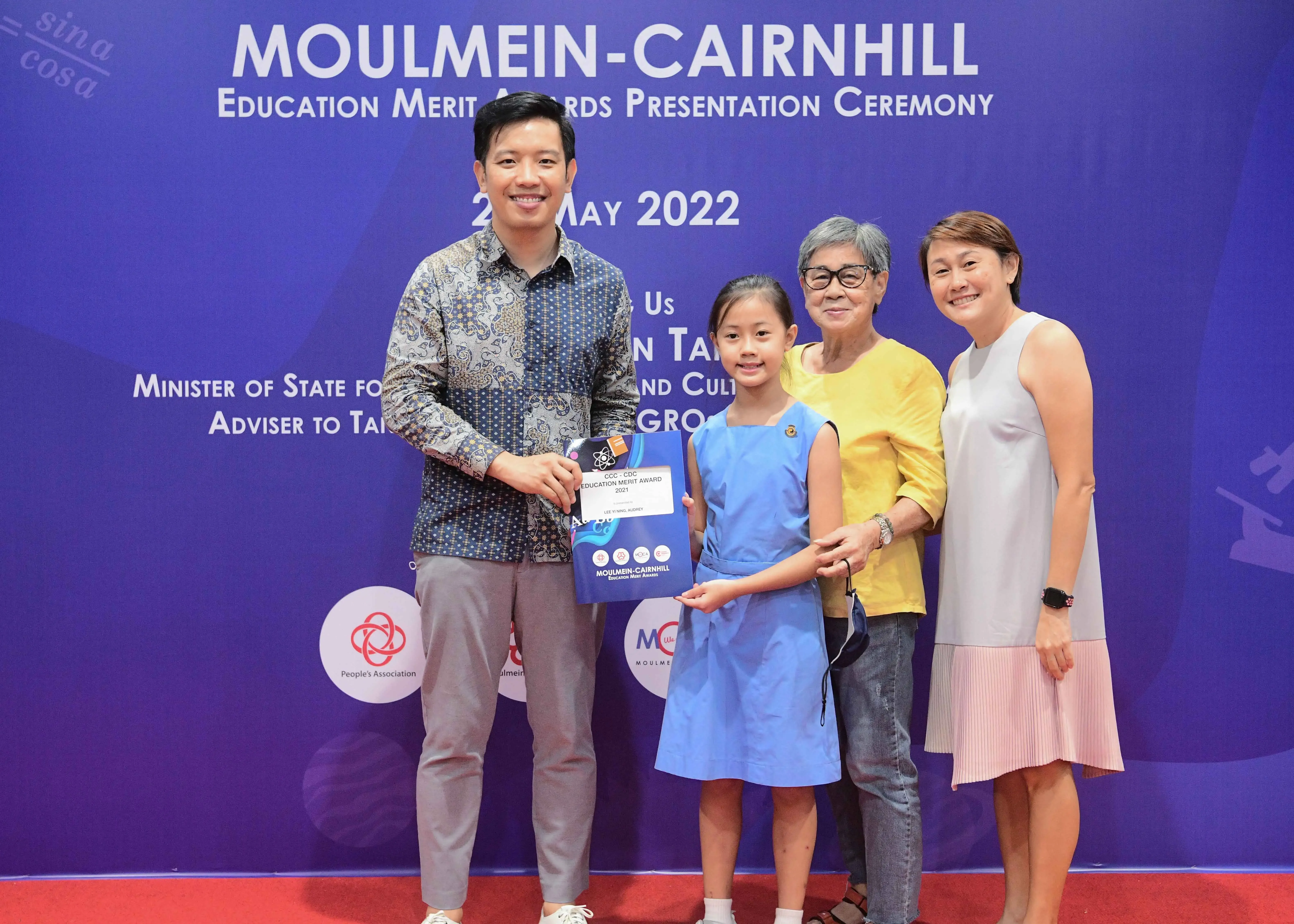Four people pose with an award certificate at the Moulmein-Cairnhill Education Merit Awards Ceremony, May 2022.