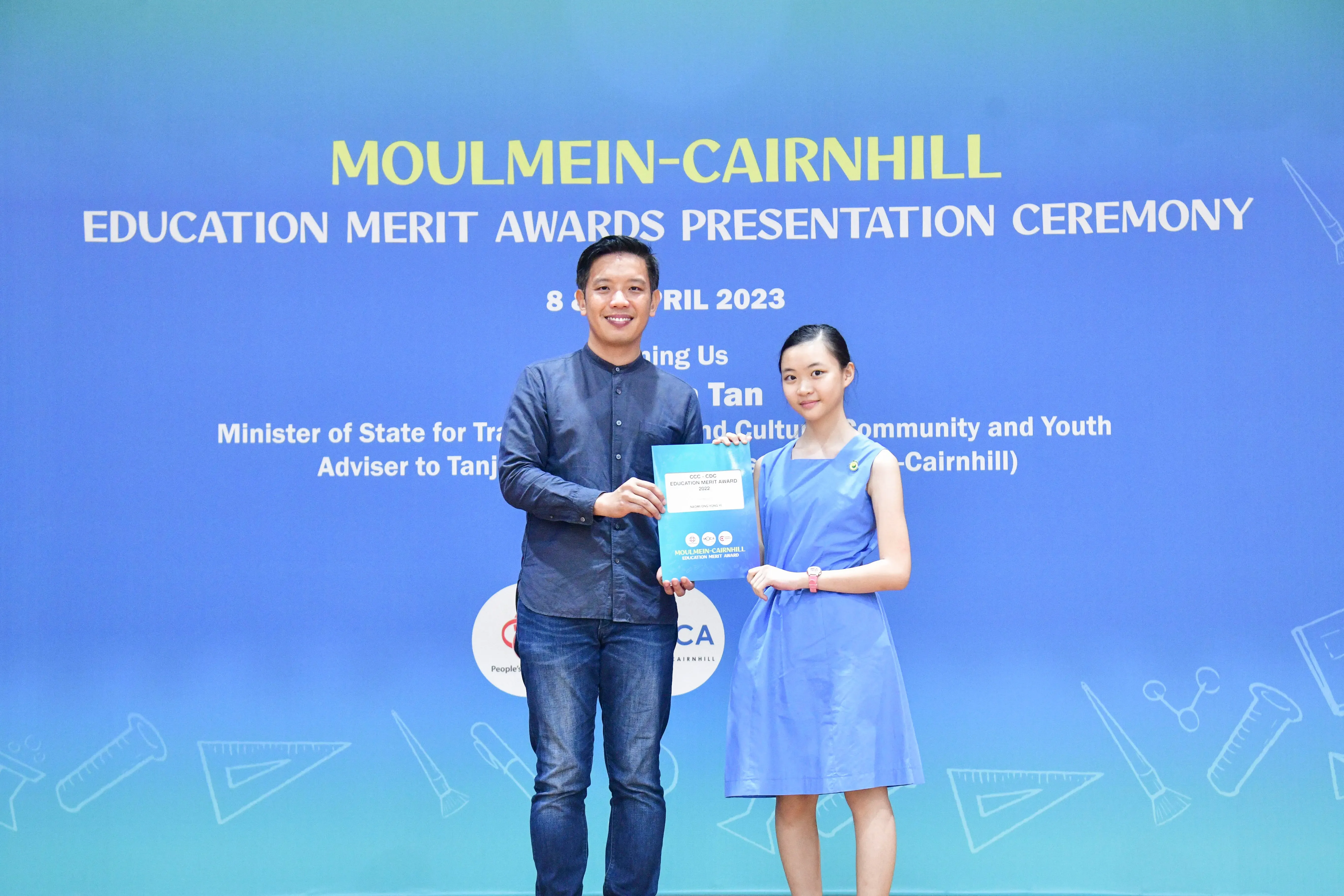 Two people hold an award certificate at the Moulmein-Cairnhill Education Merit Awards Presentation Ceremony, April 2023.