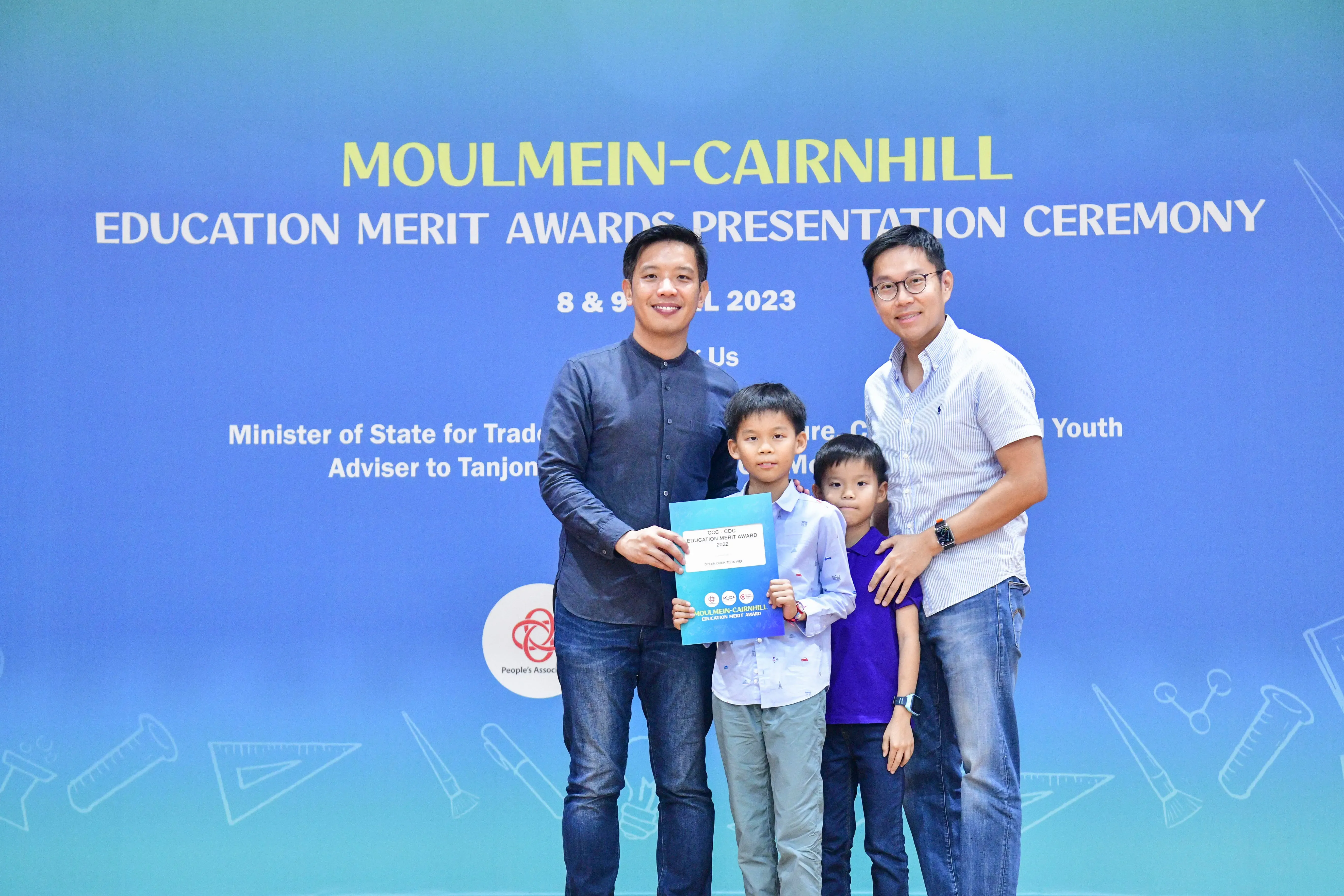 Two men and two boys pose with a certificate at the Moulmein-Cairnhill Education Merit Awards Ceremony 2023.