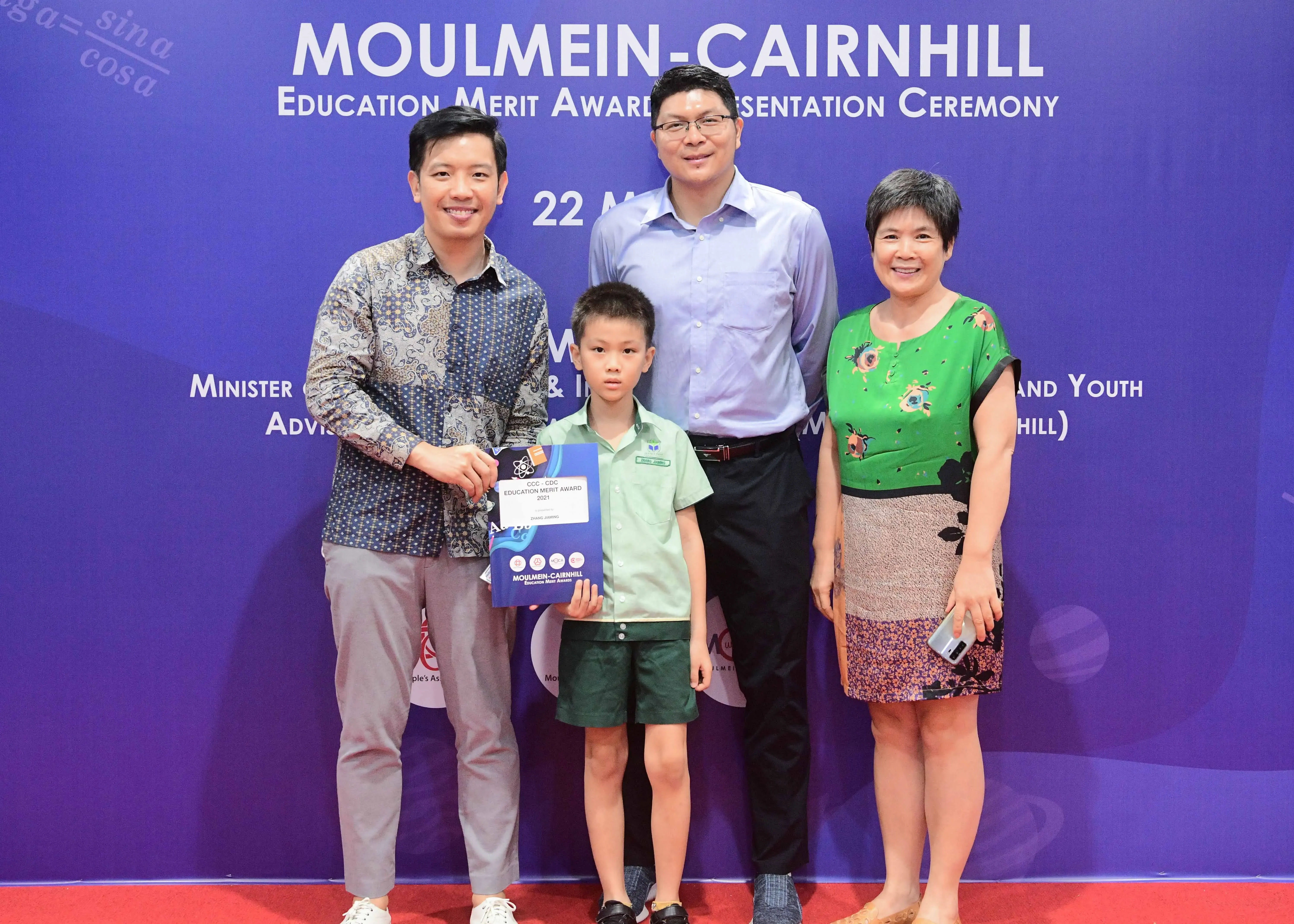 Three adults and a young boy pose at the Moulmein-Cairnhill Education Merit Award Presentation Ceremony.