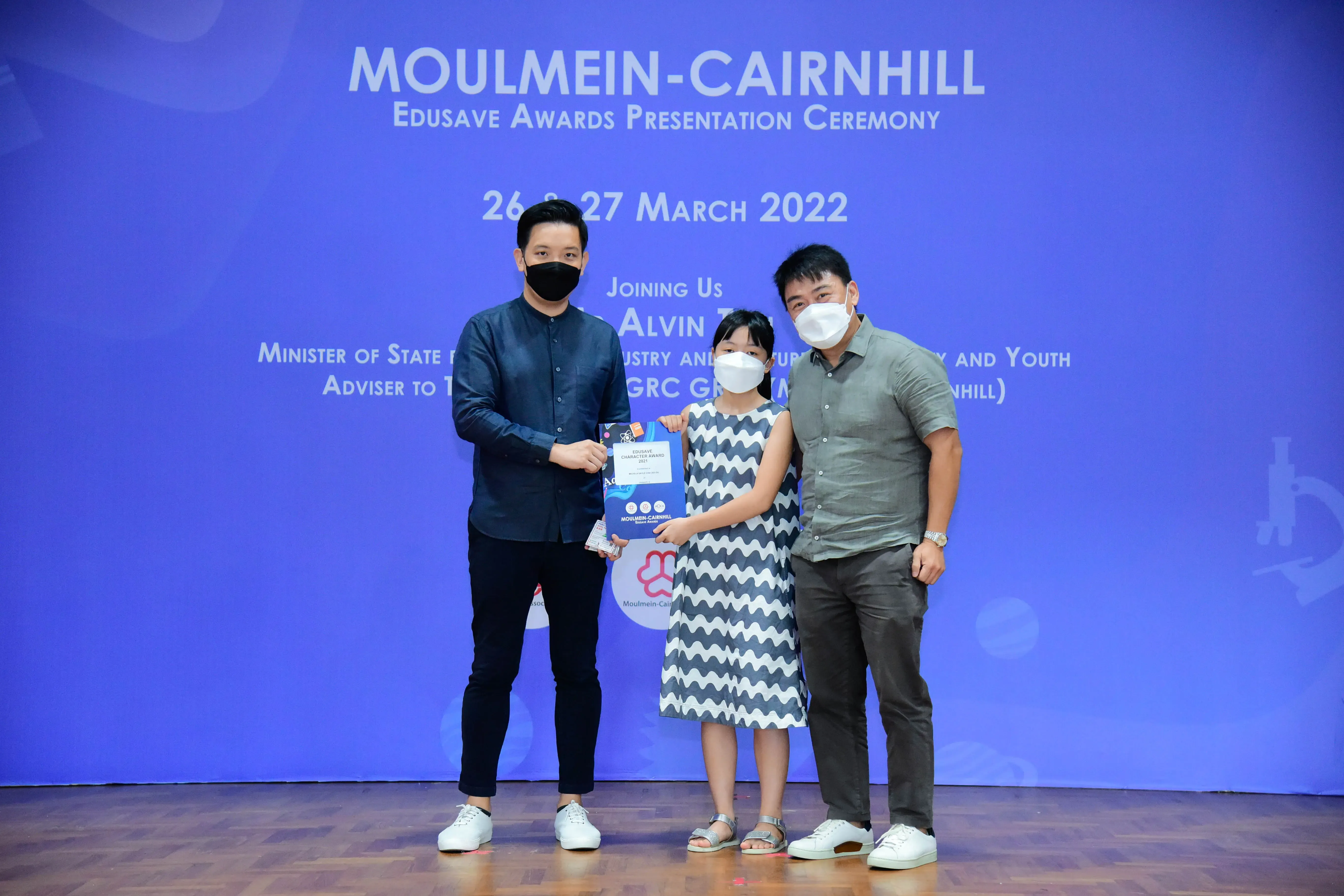 Three masked people pose at the Moulmein-Cairnhill Edusave Awards Ceremony on 26-27 March 2022.