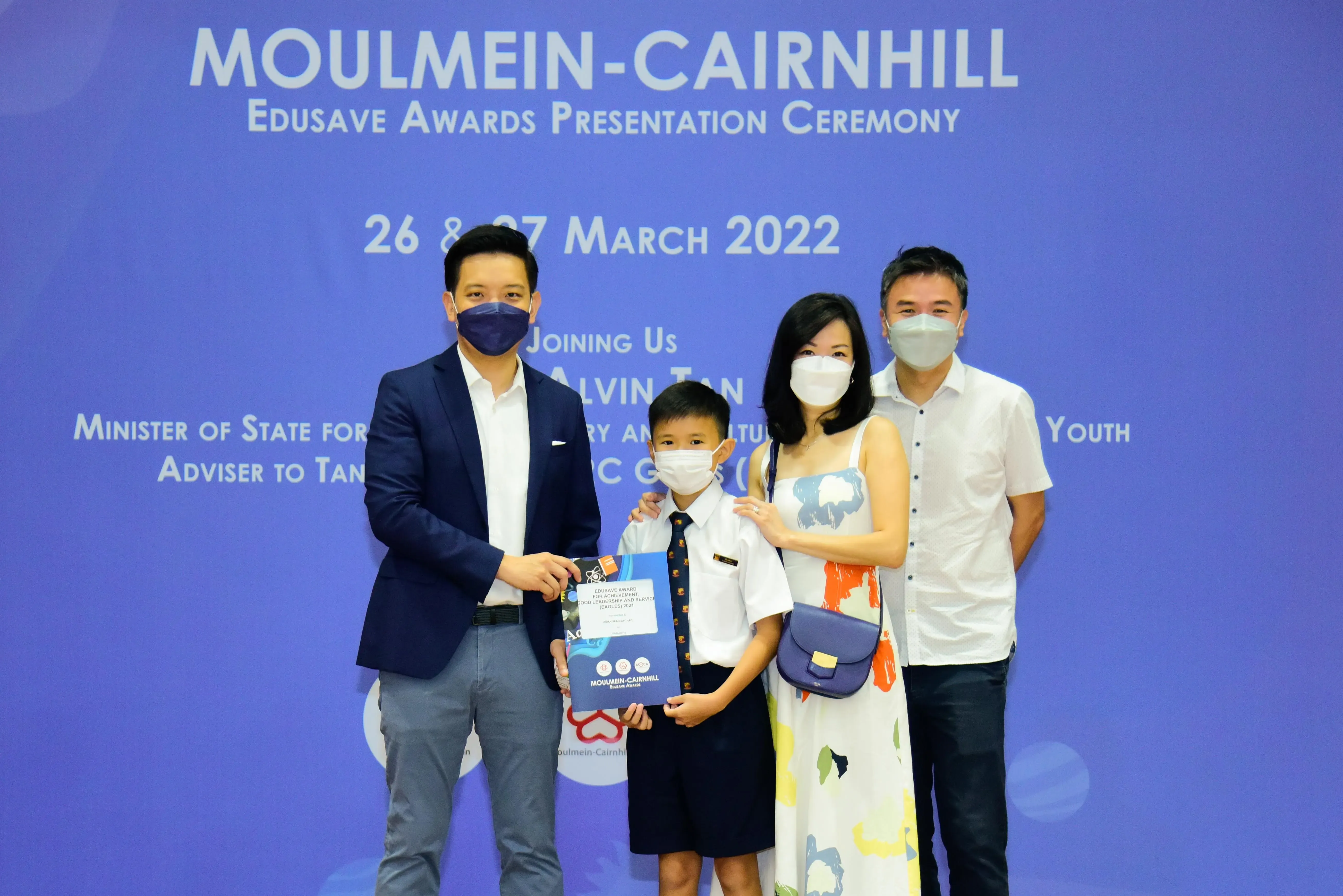 Four masked people pose at the Moulmein-Cairnhill Edusave Awards Presentation Ceremony in March 2022.