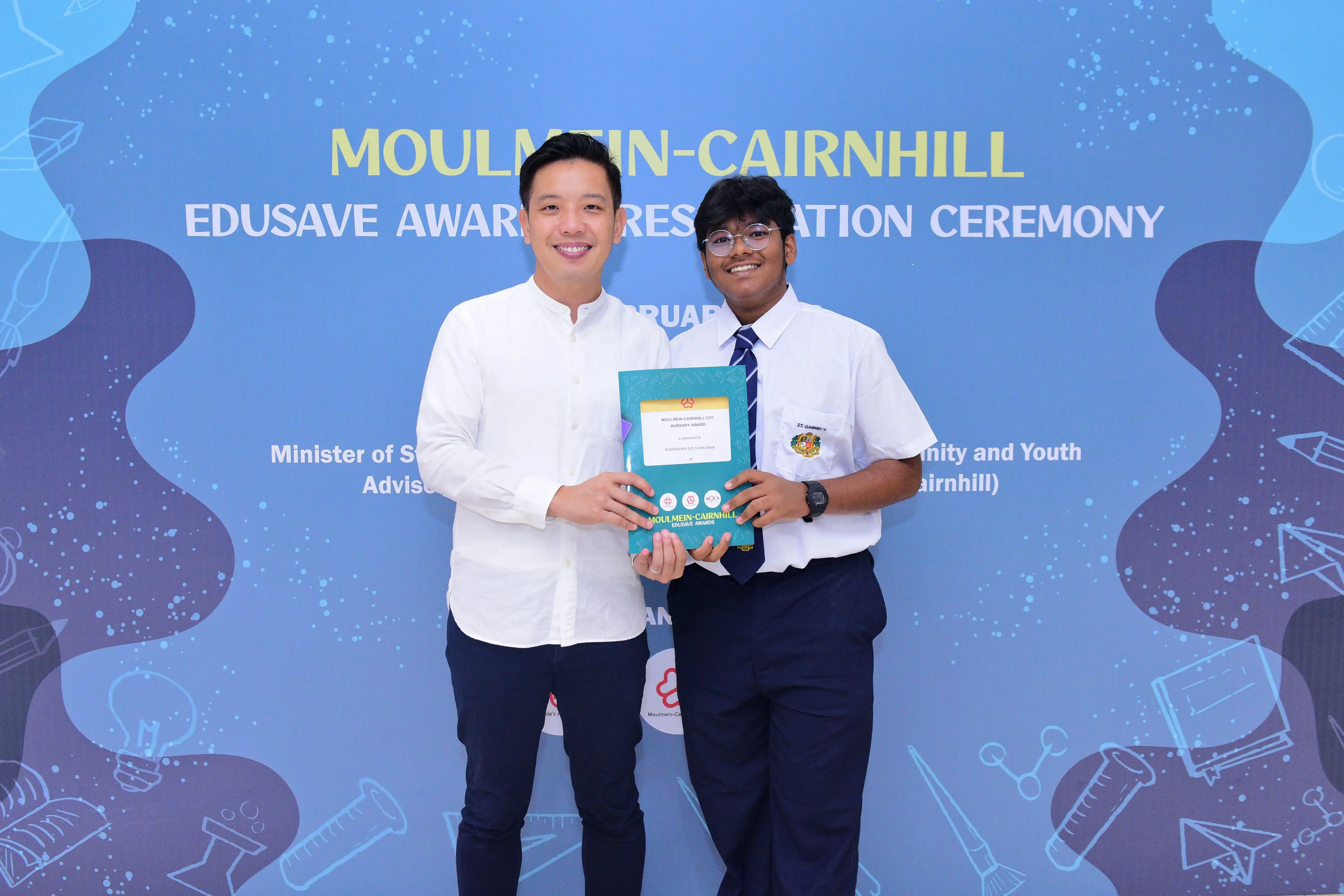 Two smiling people hold a certificate together at the Moulmein-Cairnhill Edusave Awards Presentation Ceremony.