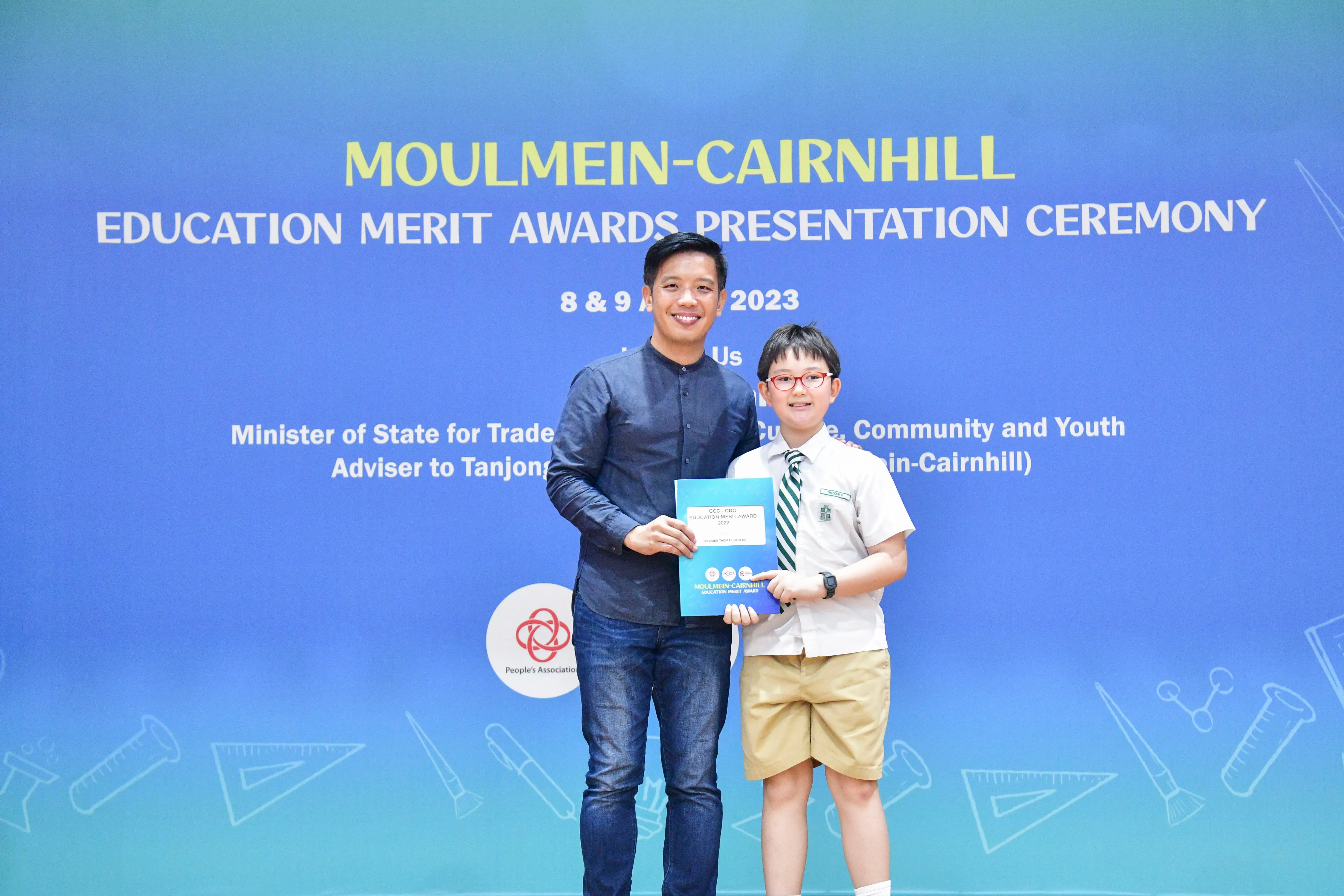An adult and a young student in school uniform hold a certificate at the Moulmein-Cairnhill Education Merit Awards 2023.