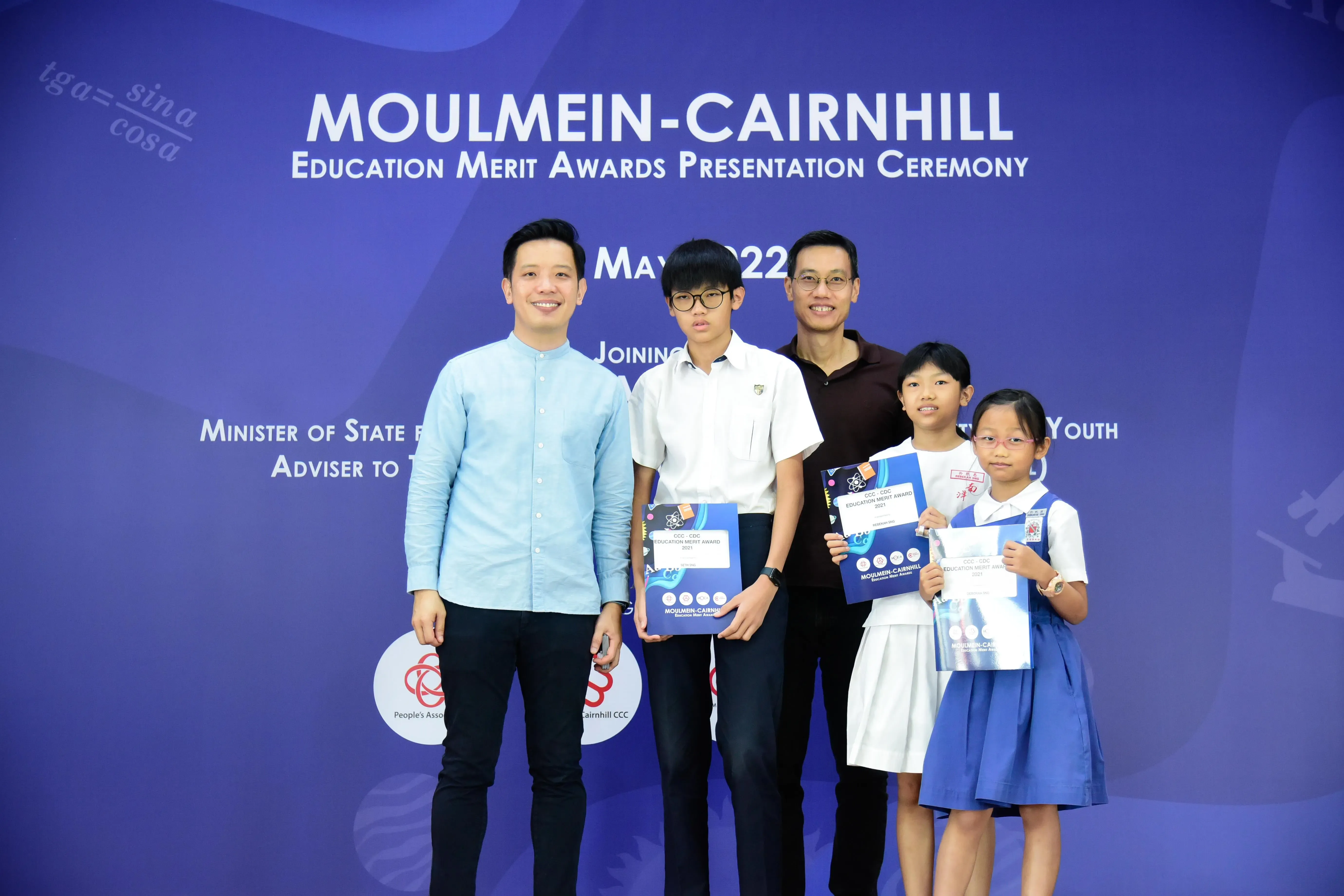 Two adults and three children pose with award certificates at the Moulmein-Cairnhill Education Merit Awards ceremony in May 2022.