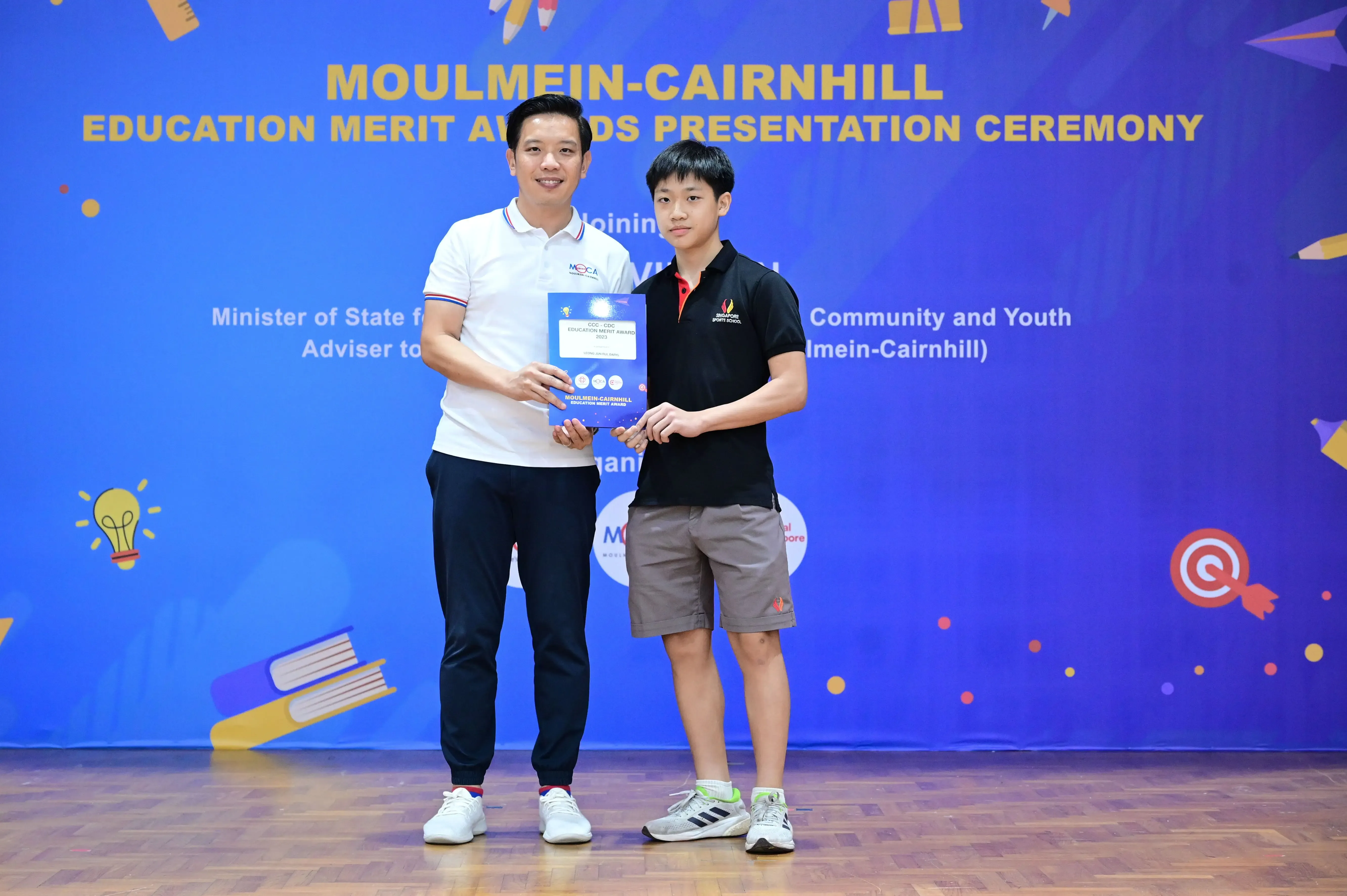 Two people hold an award certificate at the Moulmein-Cairnhill Education Merit Awards Presentation Ceremony.