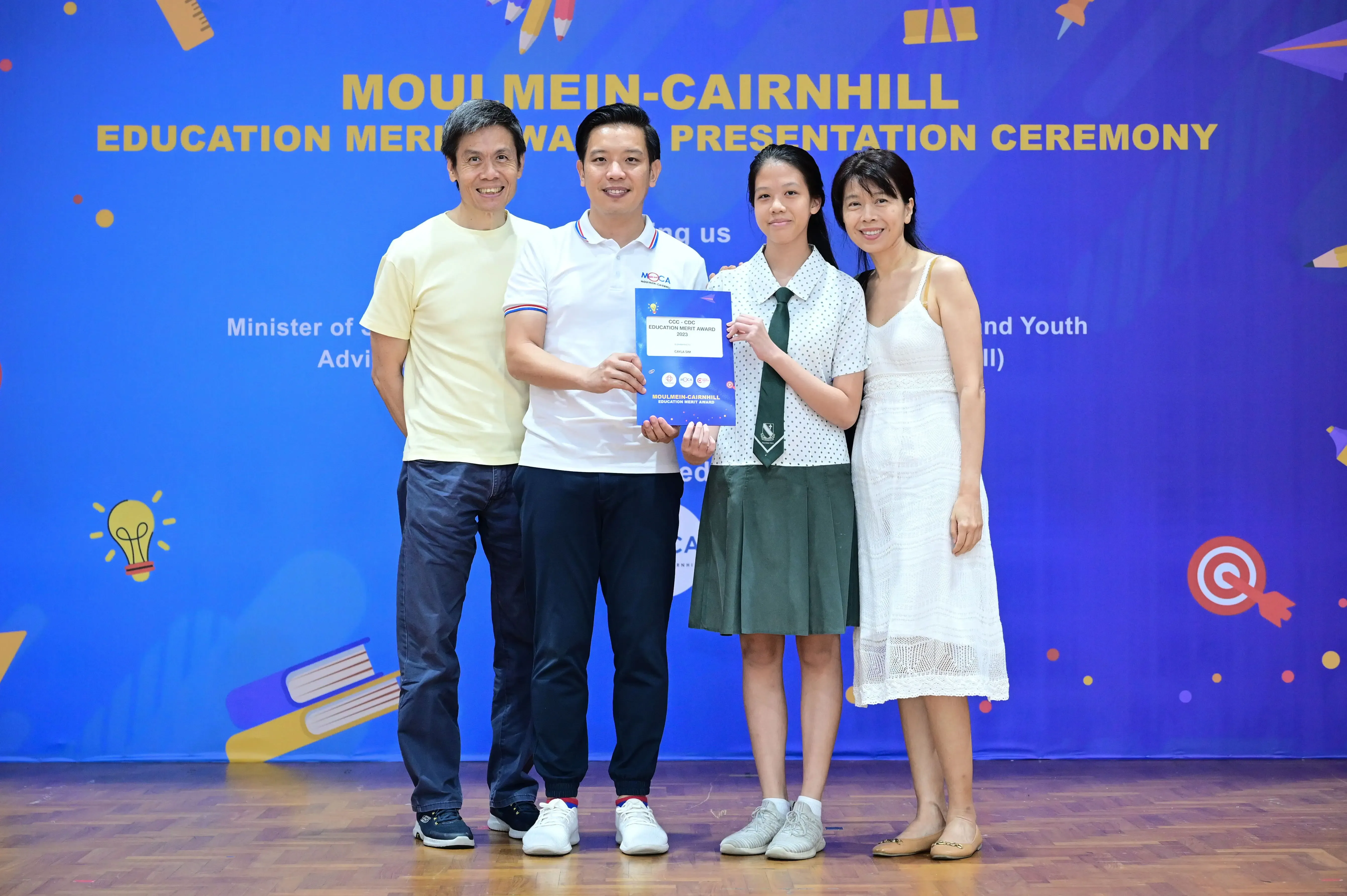 Four people pose holding an award certificate at the Moulmein-Cairnhill Education Merit Award Presentation Ceremony.