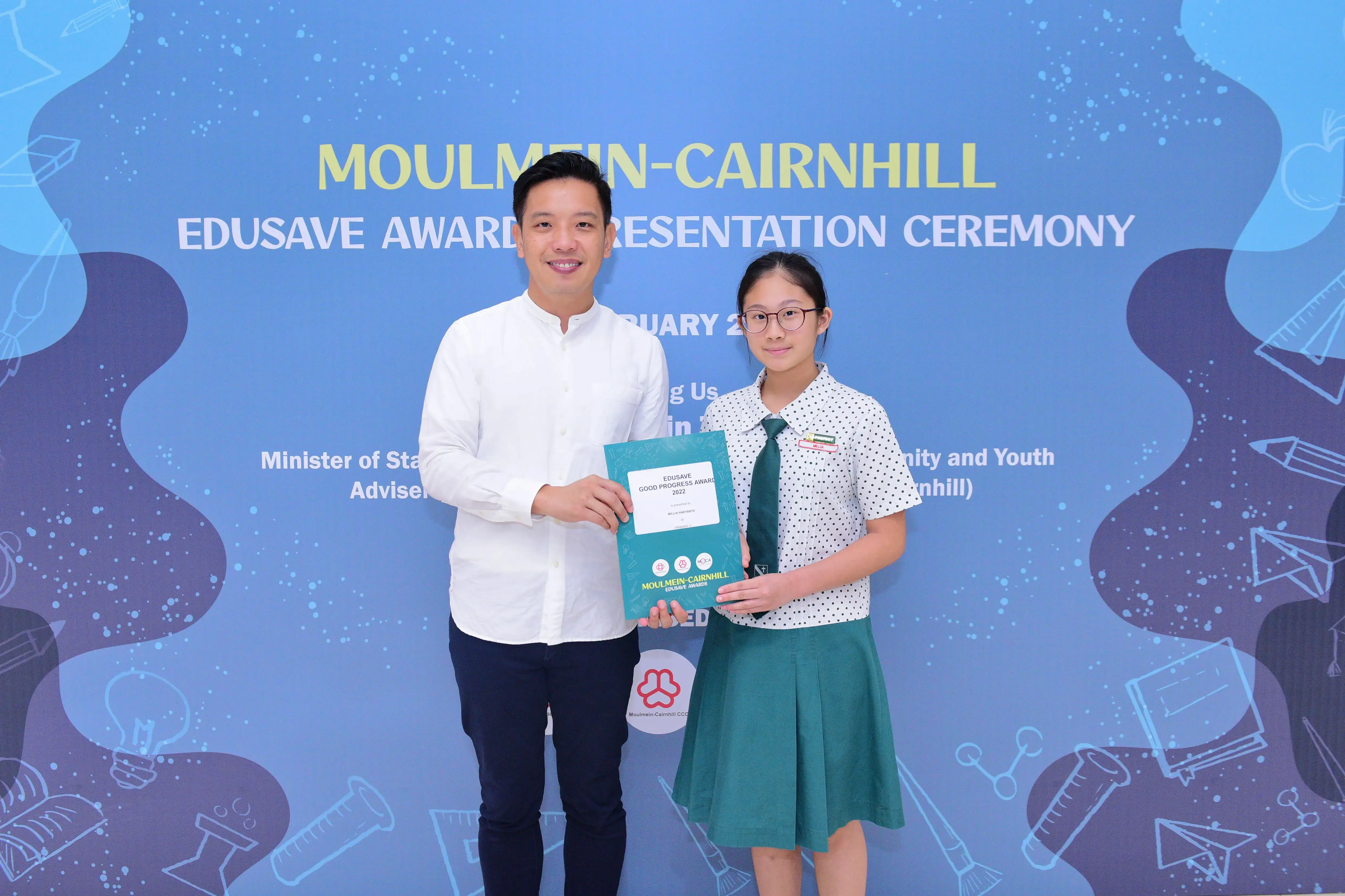 A man and a young girl hold an Edusave award certificate at the Moulmein-Cairnhill Award Presentation Ceremony.