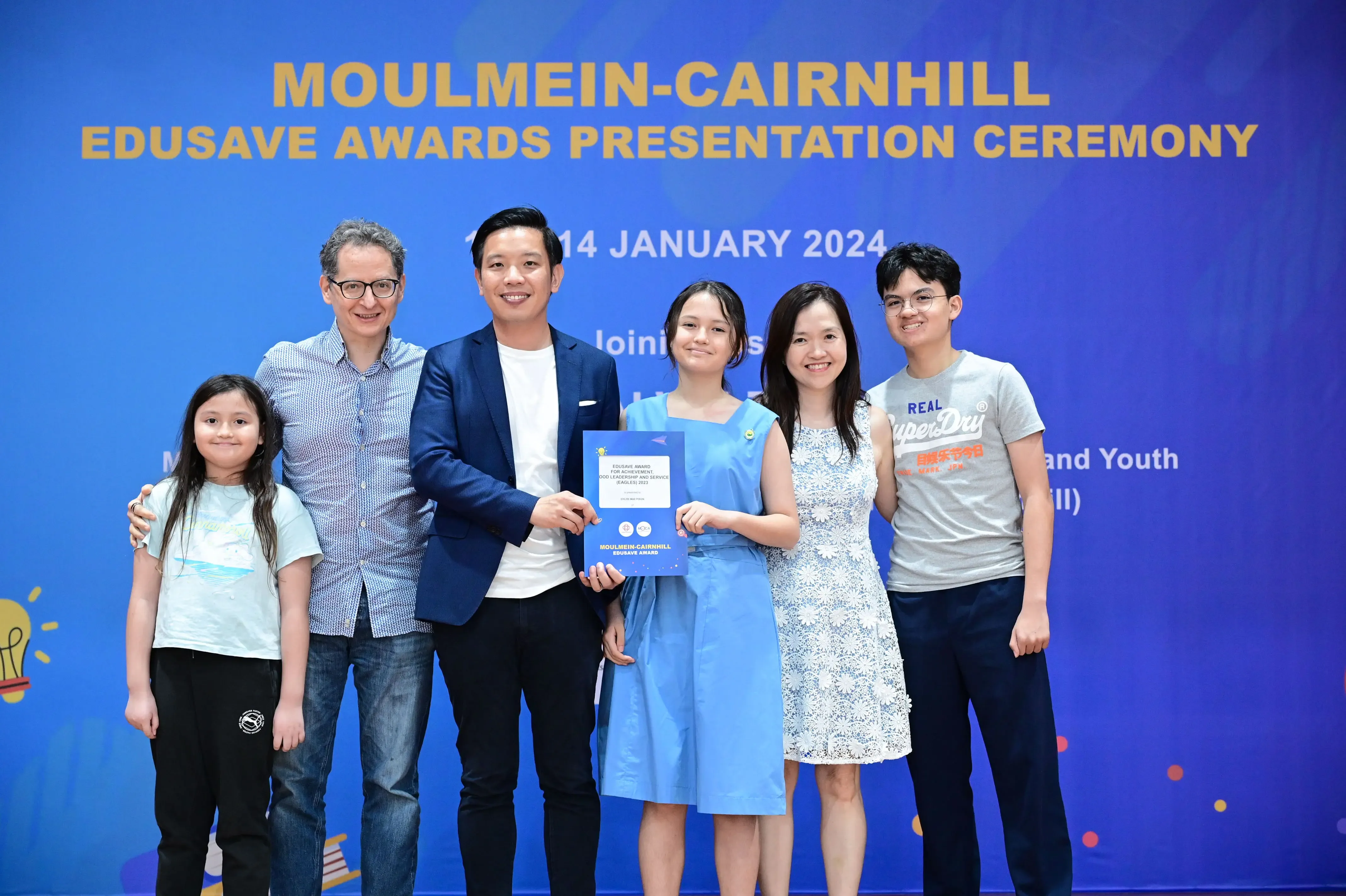 Six people pose holding a certificate at the Moulmein-Cairnhill Edusave Awards Presentation Ceremony, January 2024.
