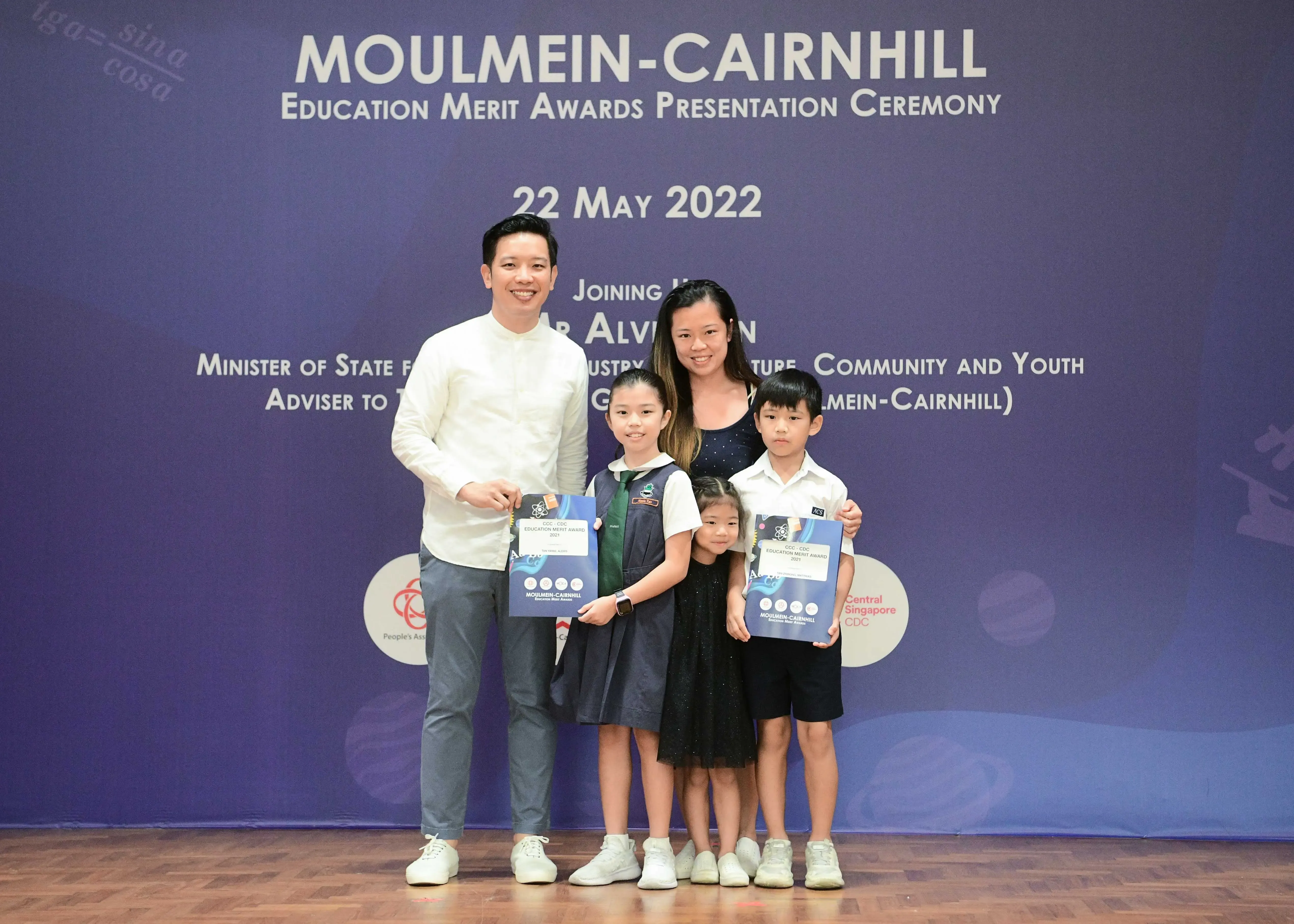 Two adults and three children pose with award booklets at the Moulmein-Cairnhill Education Merit Awards Ceremony, 22 May 2022.