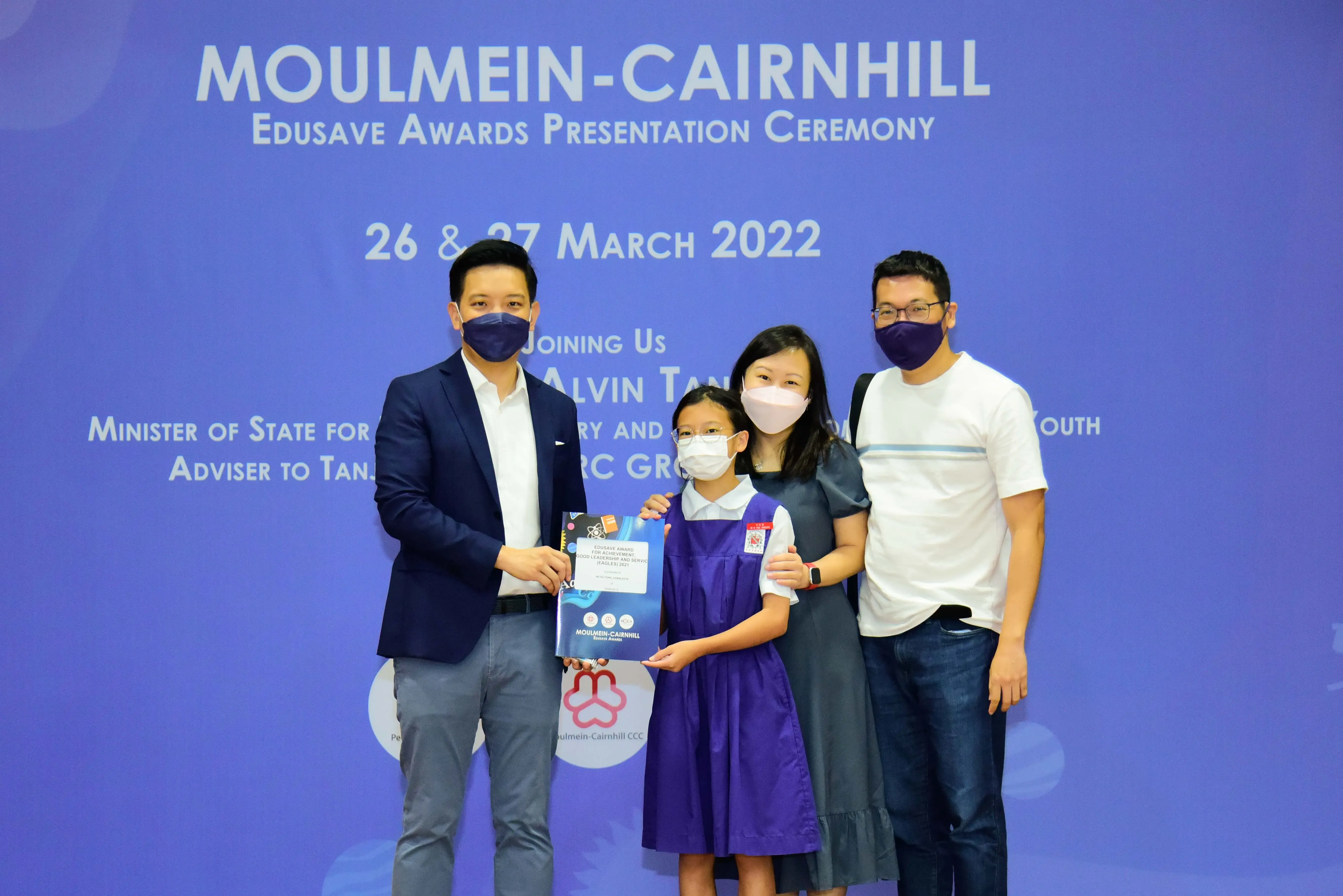 Four masked people pose at the Moulmein-Cairnhill Edusave Awards Presentation Ceremony on 26-27 March 2022.