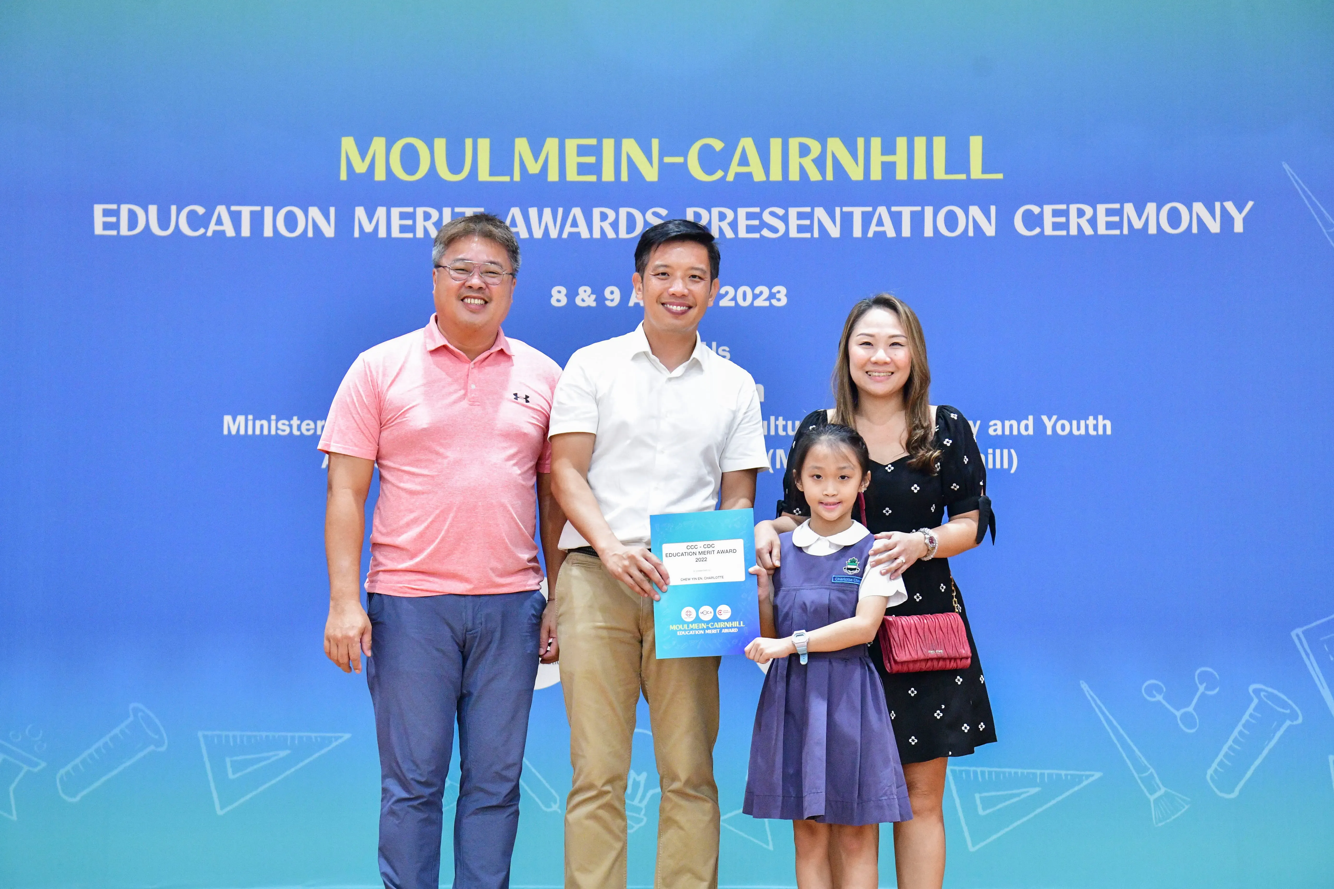 Three adults and a young girl pose with an award certificate at the Moulmein-Cairnhill Education Merit Awards 2023.