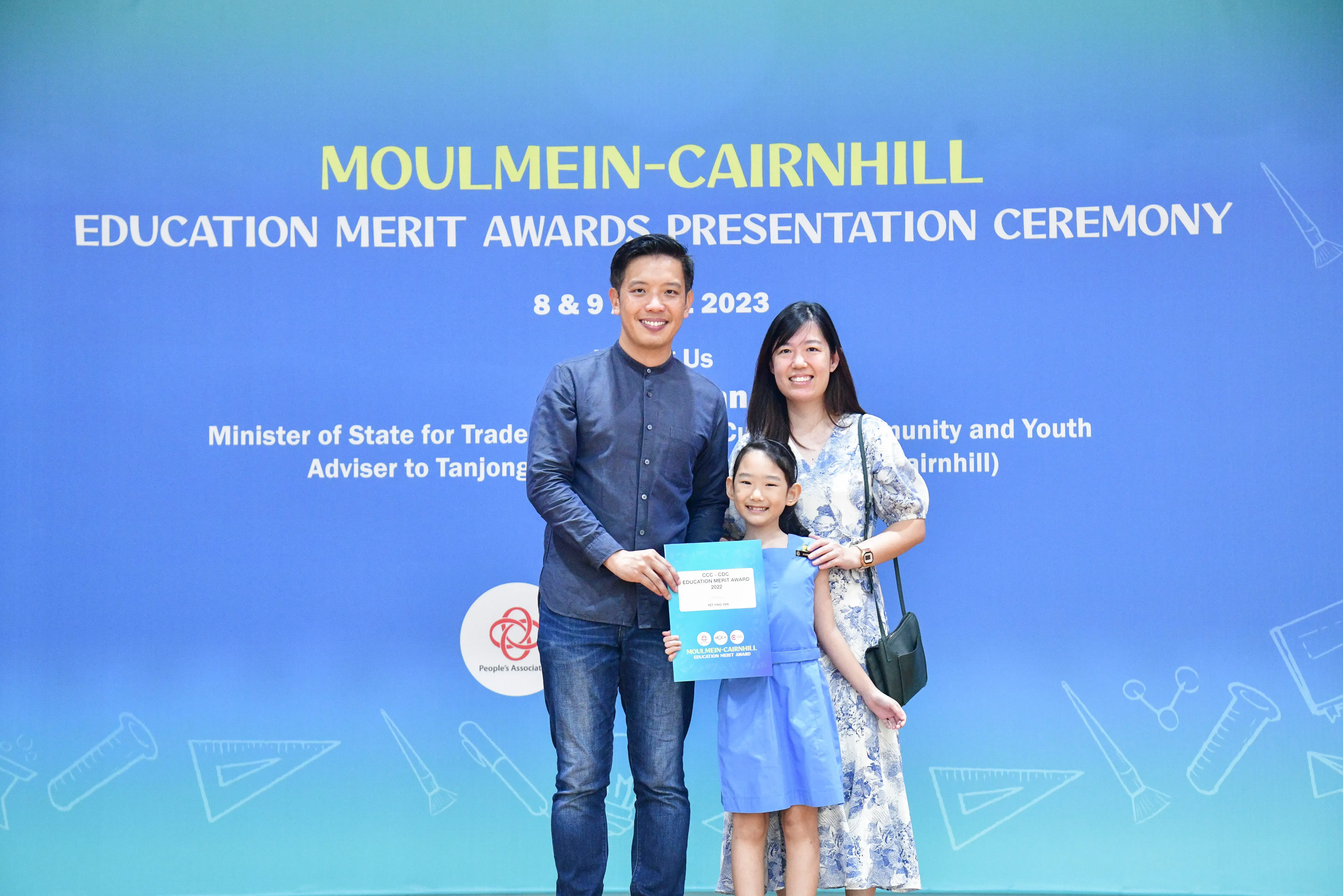 A man, woman, and young girl hold an award certificate at the Moulmein-Cairnhill Education Merit Awards 2023.