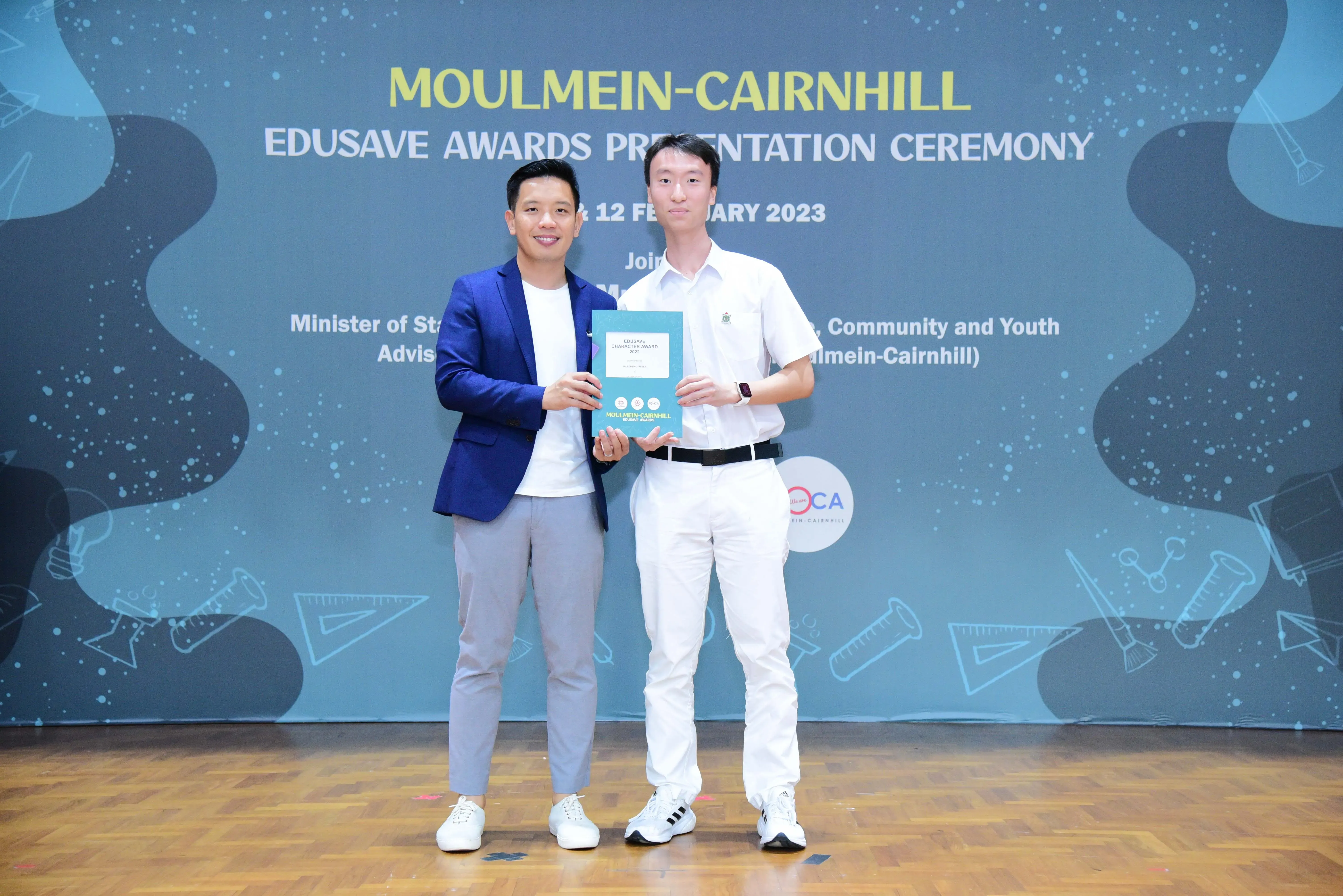 Two men hold an award certificate at the Moulmein-Cairnhill Edusave Awards Presentation Ceremony, February 2023.