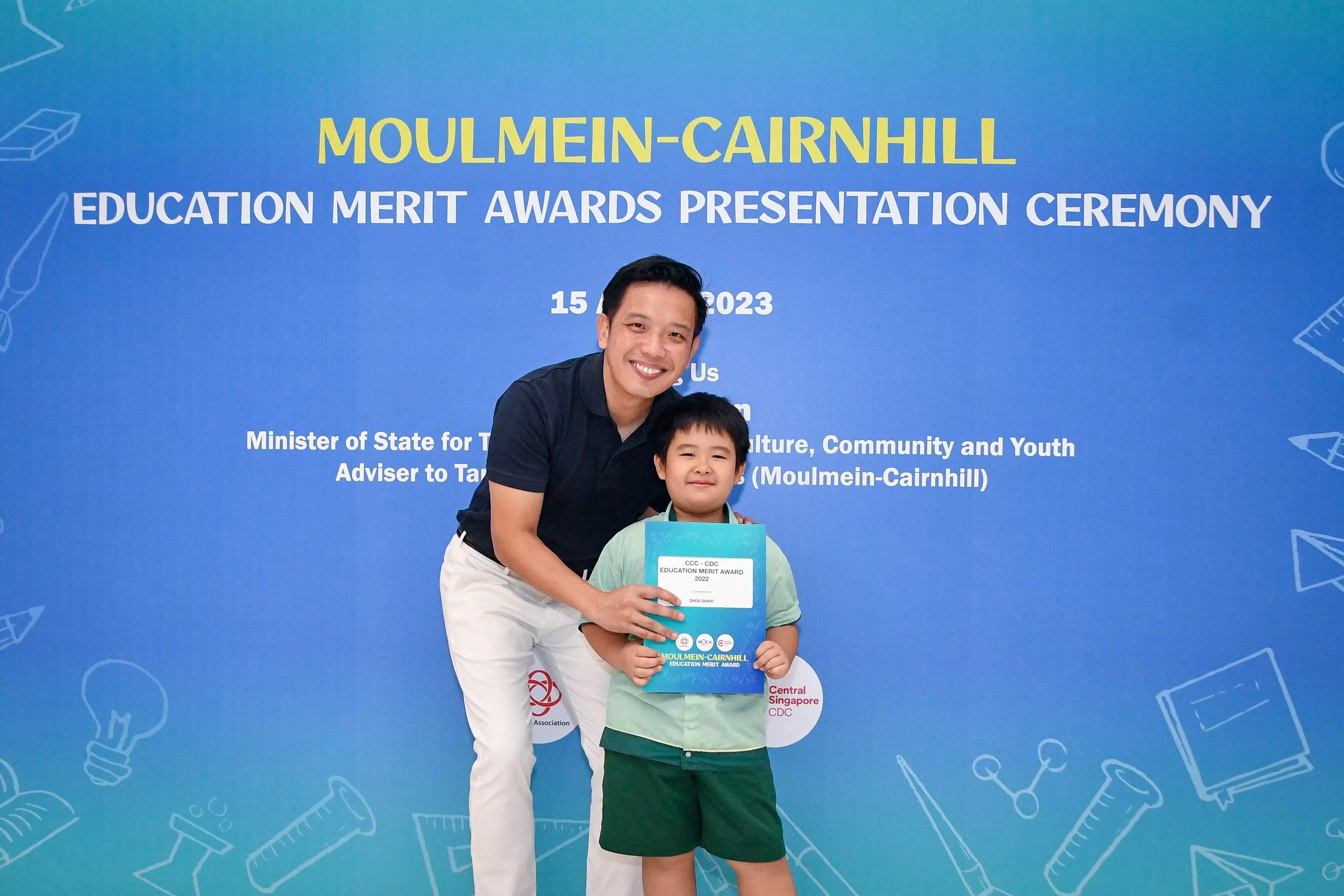 A man and a young boy pose with an award at the Moulmein-Cairnhill Education Merit Awards Ceremony 2023.