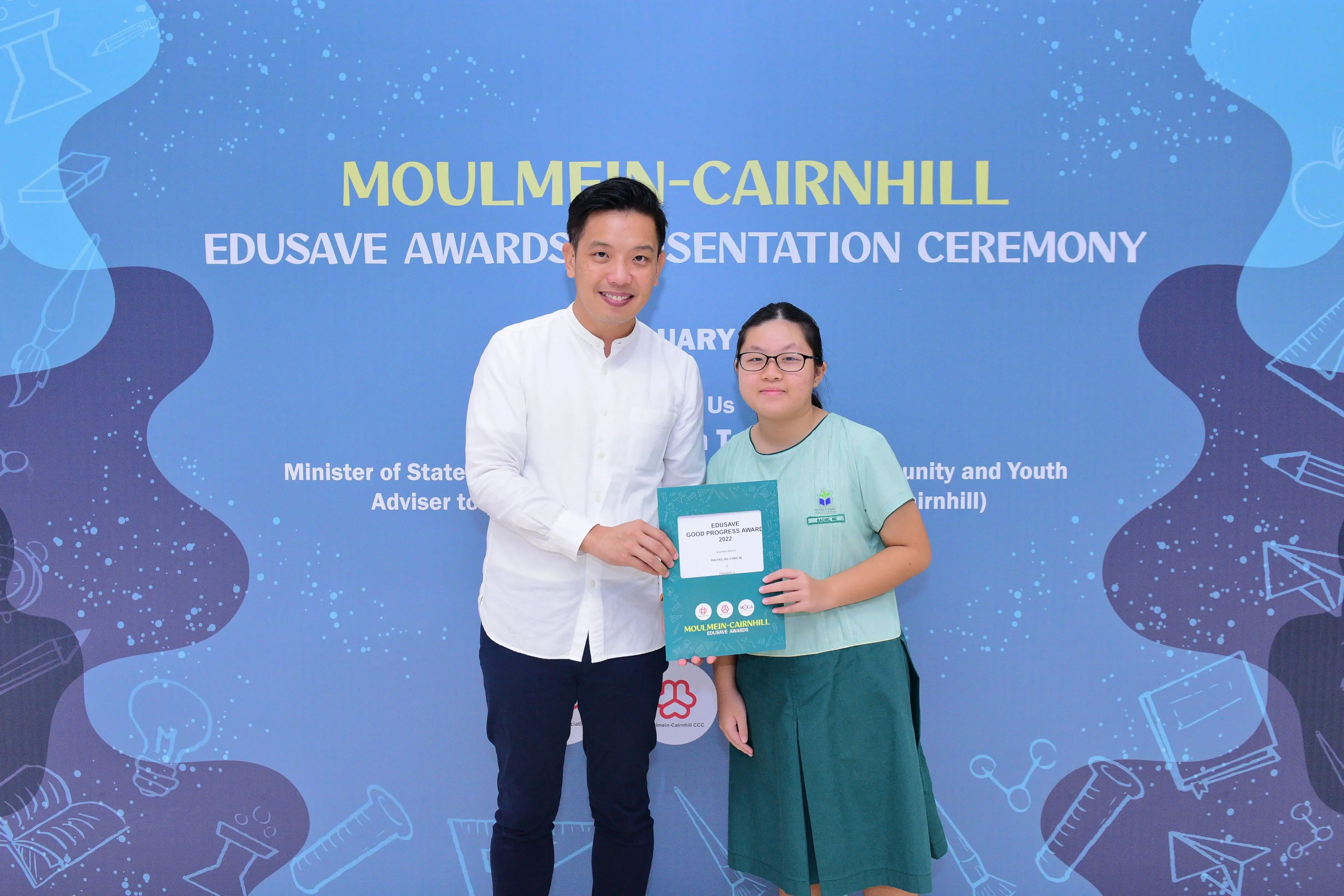 A man and a young girl hold an Edusave Good Progress Award certificate at the Moulmein-Cairnhill Awards Ceremony.
