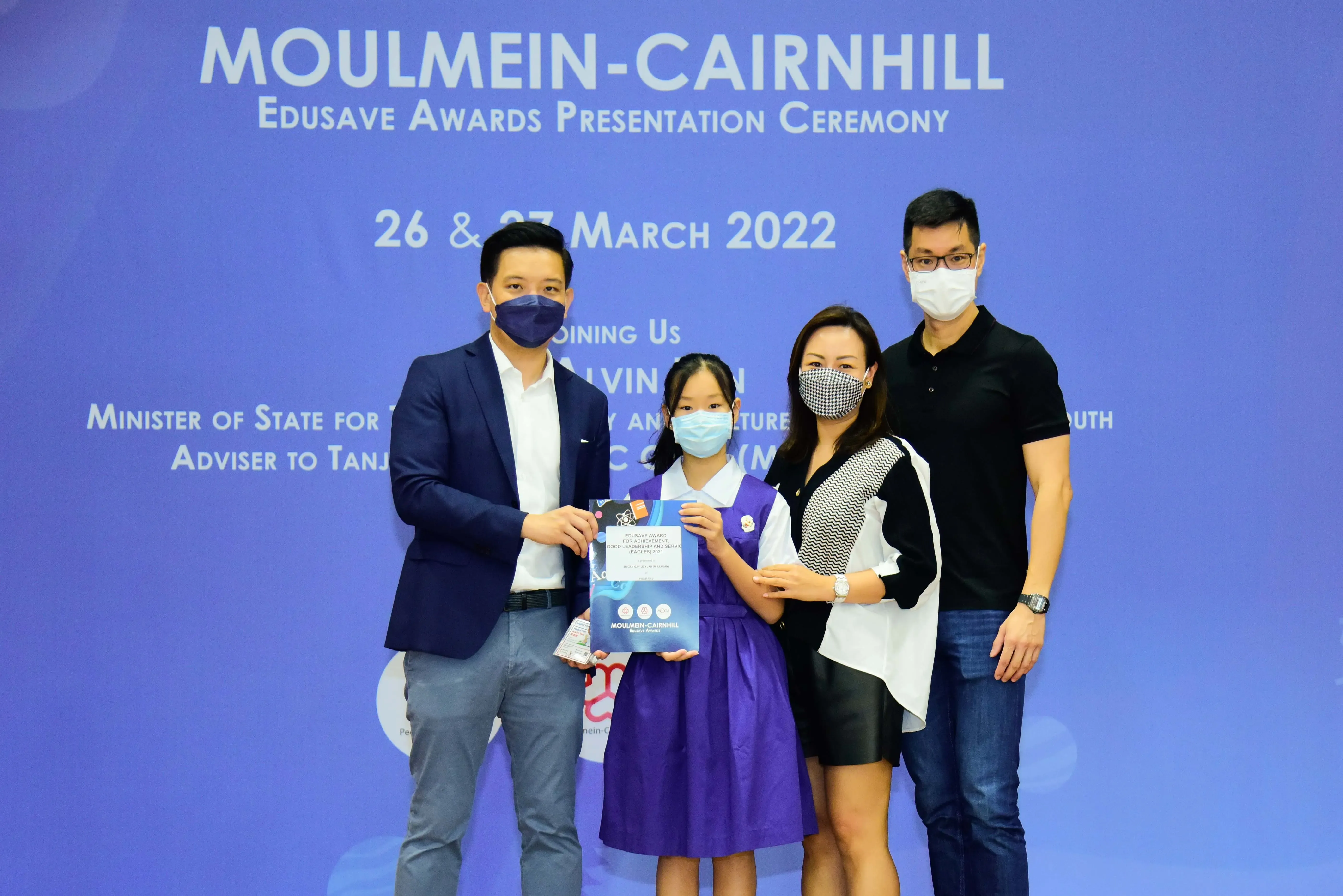 Four masked people pose at the Moulmein-Cairnhill Edusave Awards Presentation Ceremony on 26 March 2022.