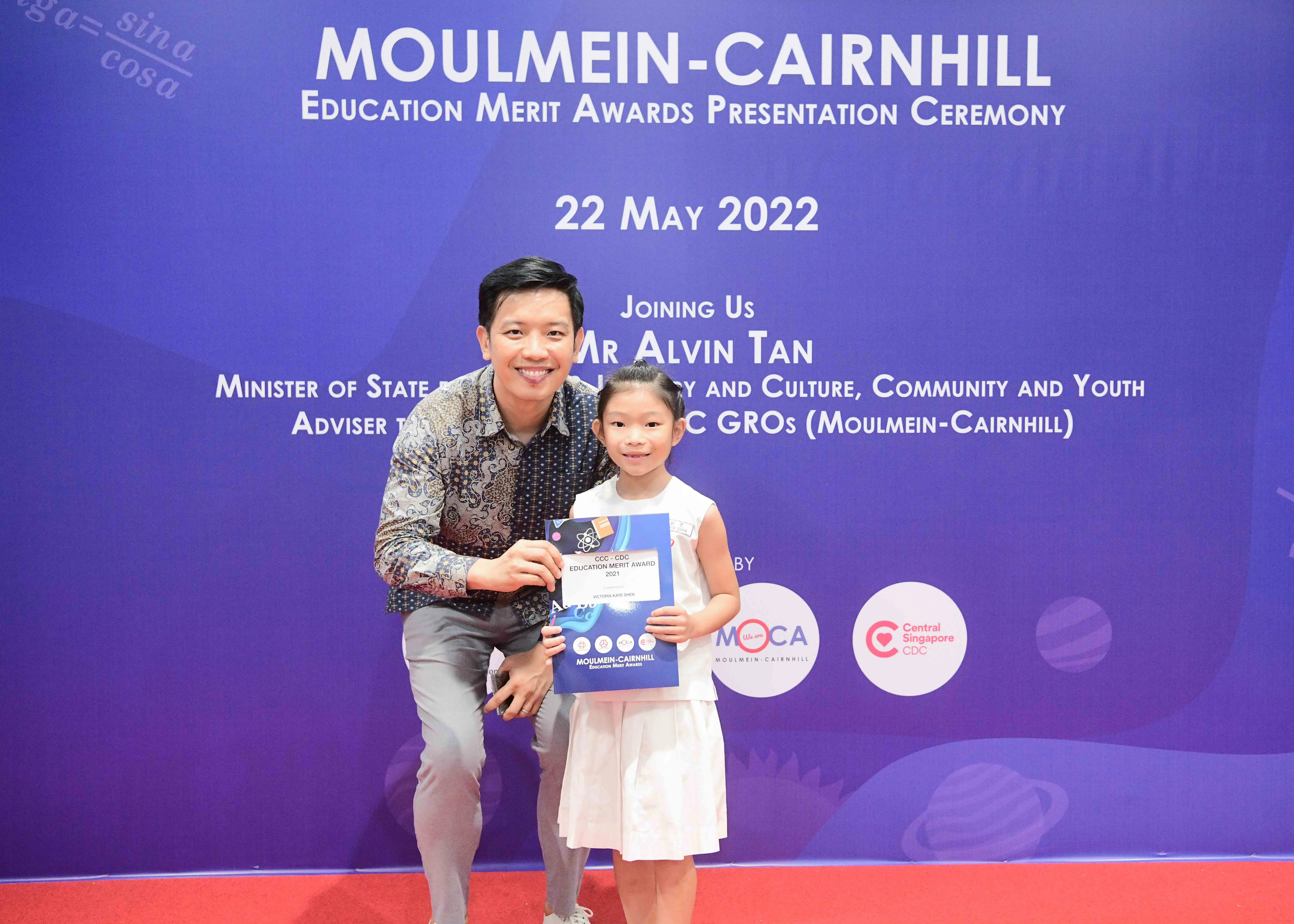 A man and a young girl hold an award certificate at the Moulmein-Cairnhill Education Merit Awards on 22 May 2022.