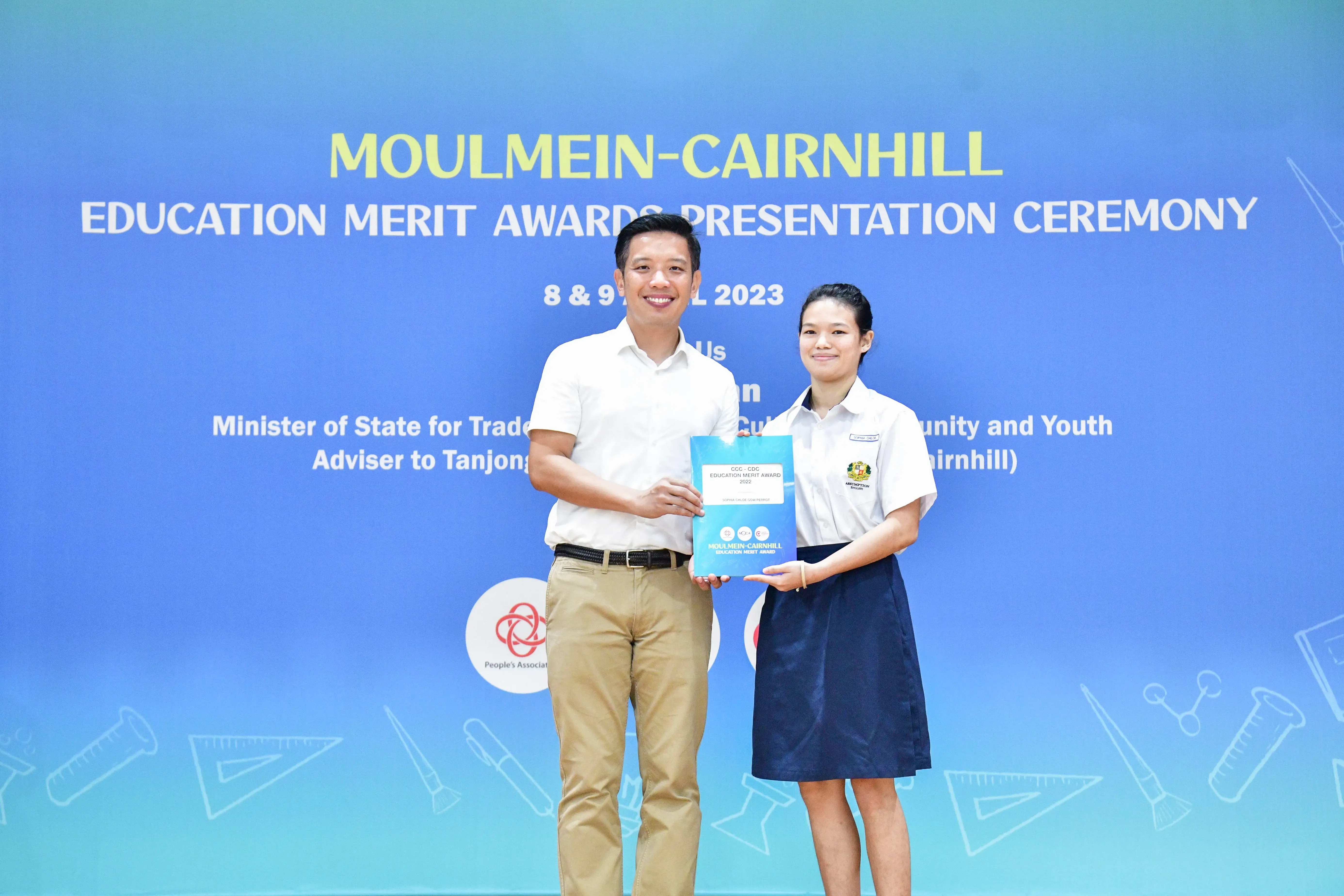 A man and a female student hold a certificate together at the Moulmein-Cairnhill Education Merit Awards 2023.