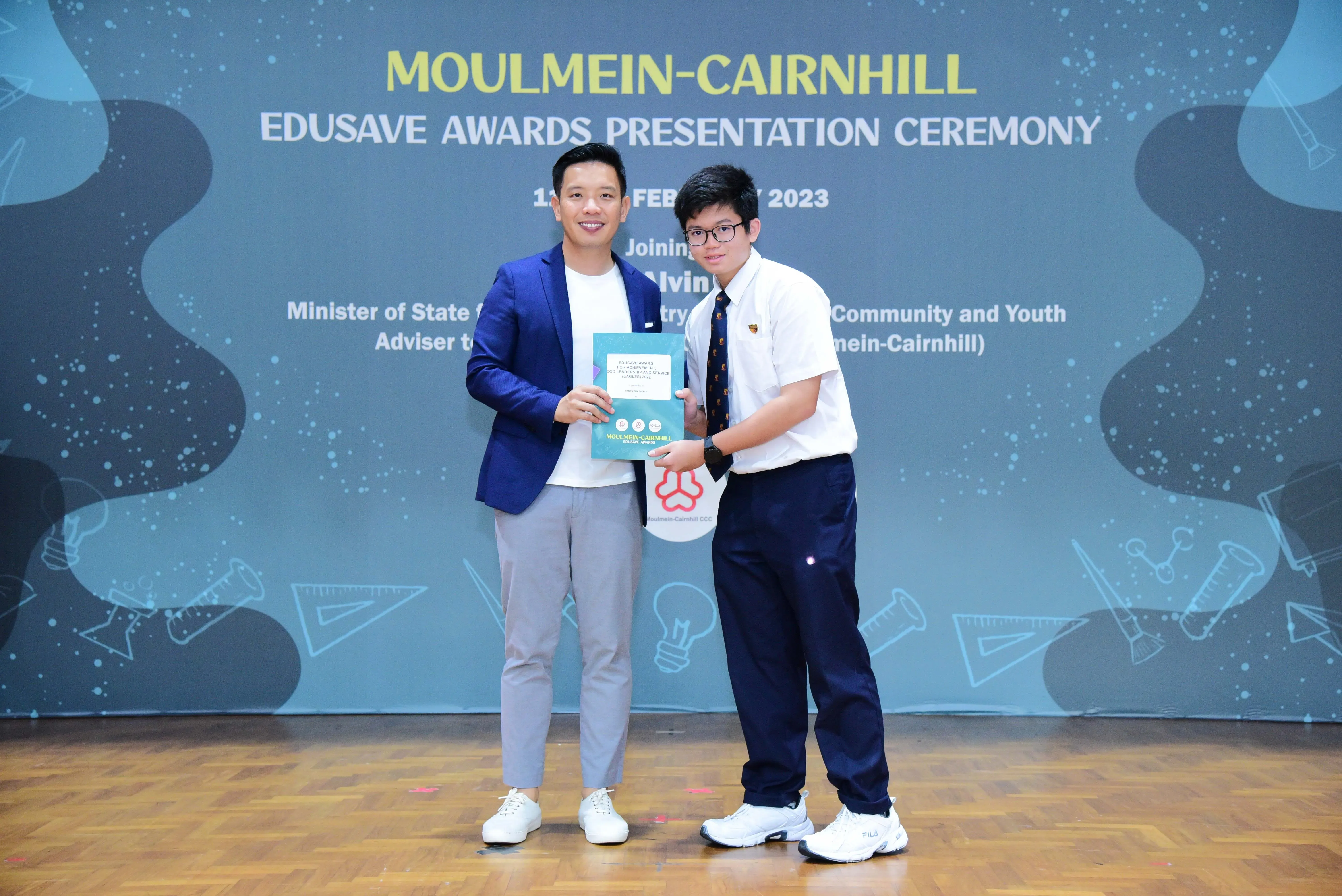 Two men hold a certificate together at the Moulmein-Cairnhill Edusave Awards Presentation Ceremony 2023.
