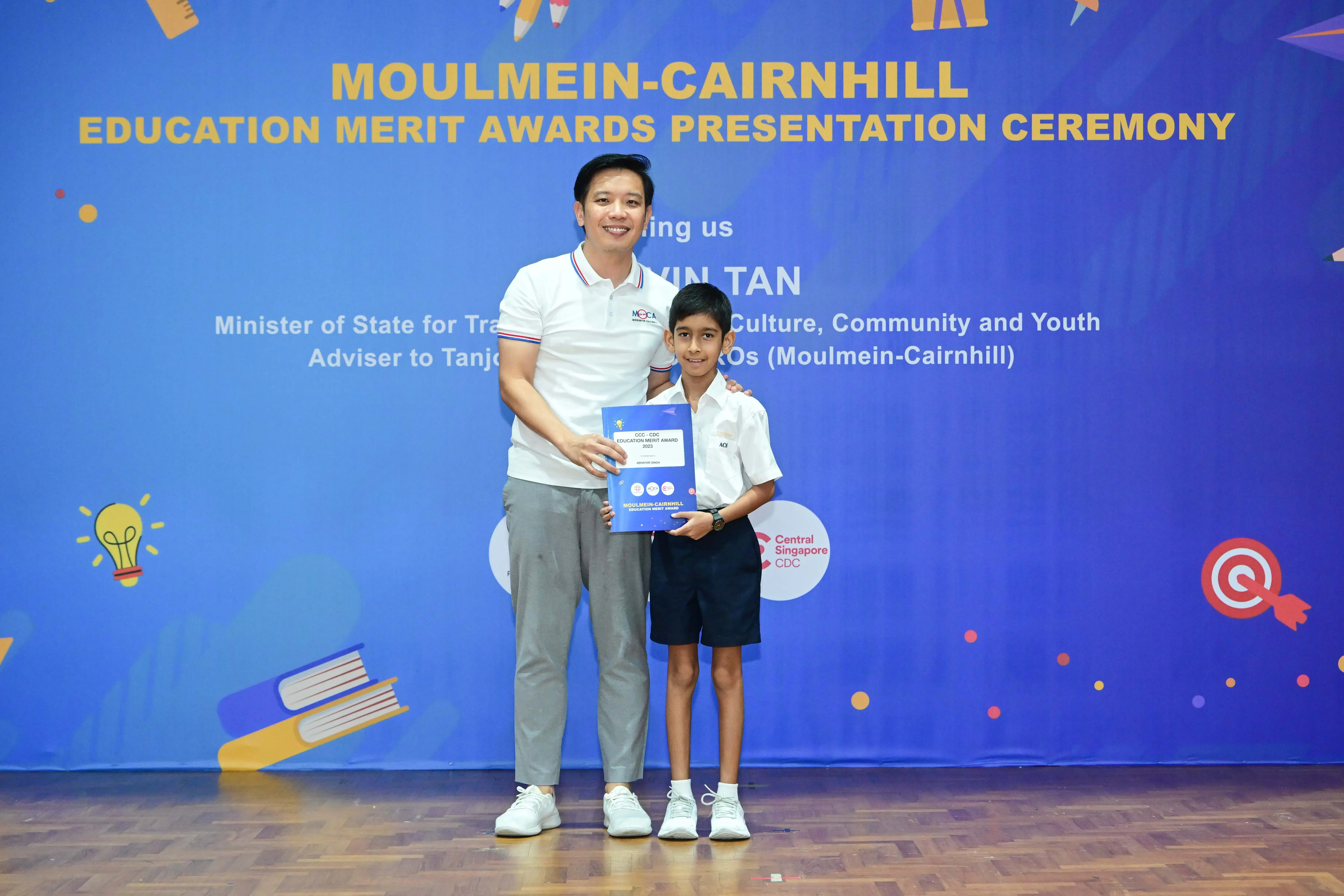 Man and young boy holding an award certificate at the Moulmein-Cairnhill Education Merit Awards Presentation Ceremony.