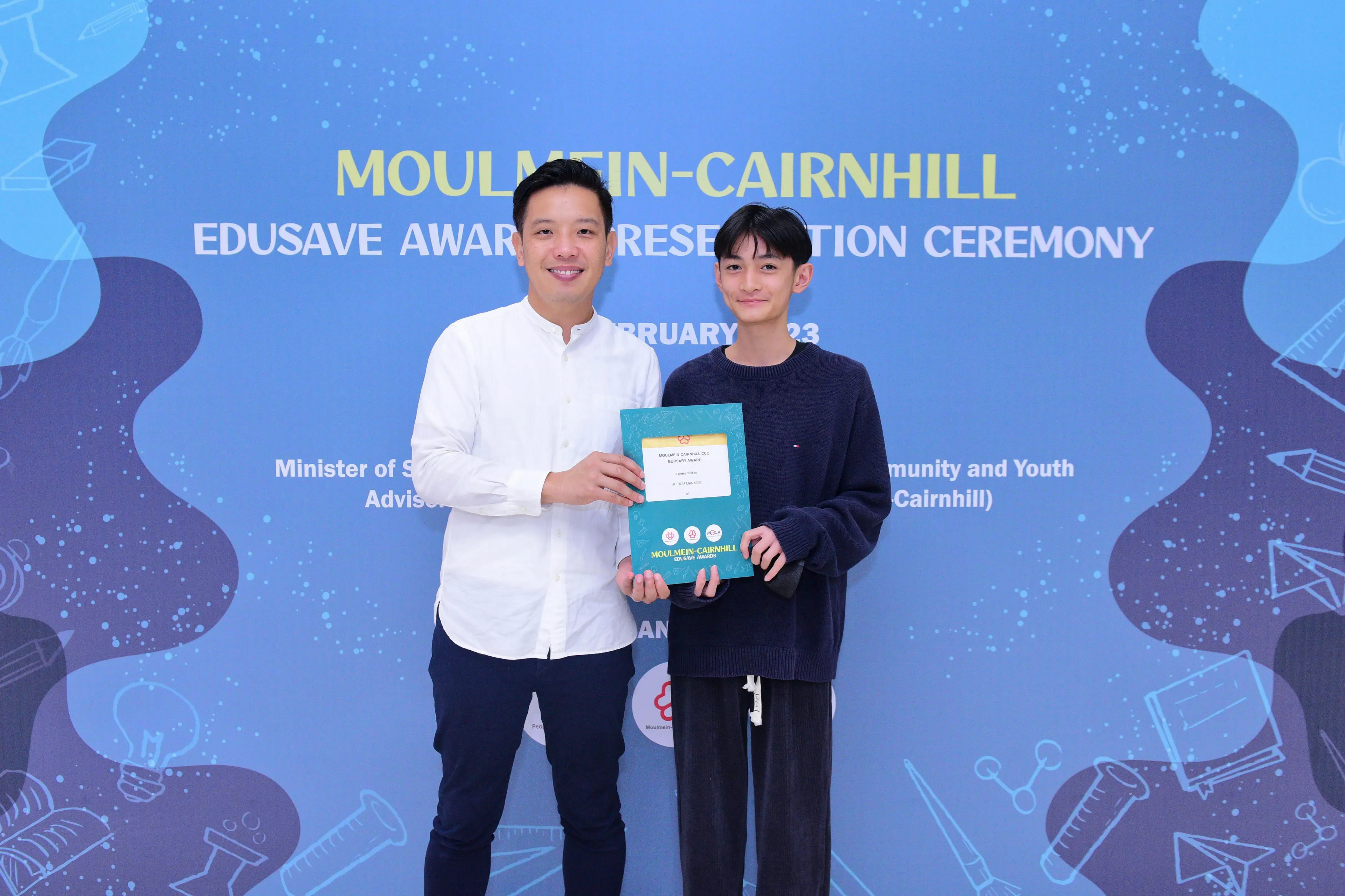 Two men pose holding a certificate at the Moulmein-Cairnhill Edusave Awards Presentation Ceremony.