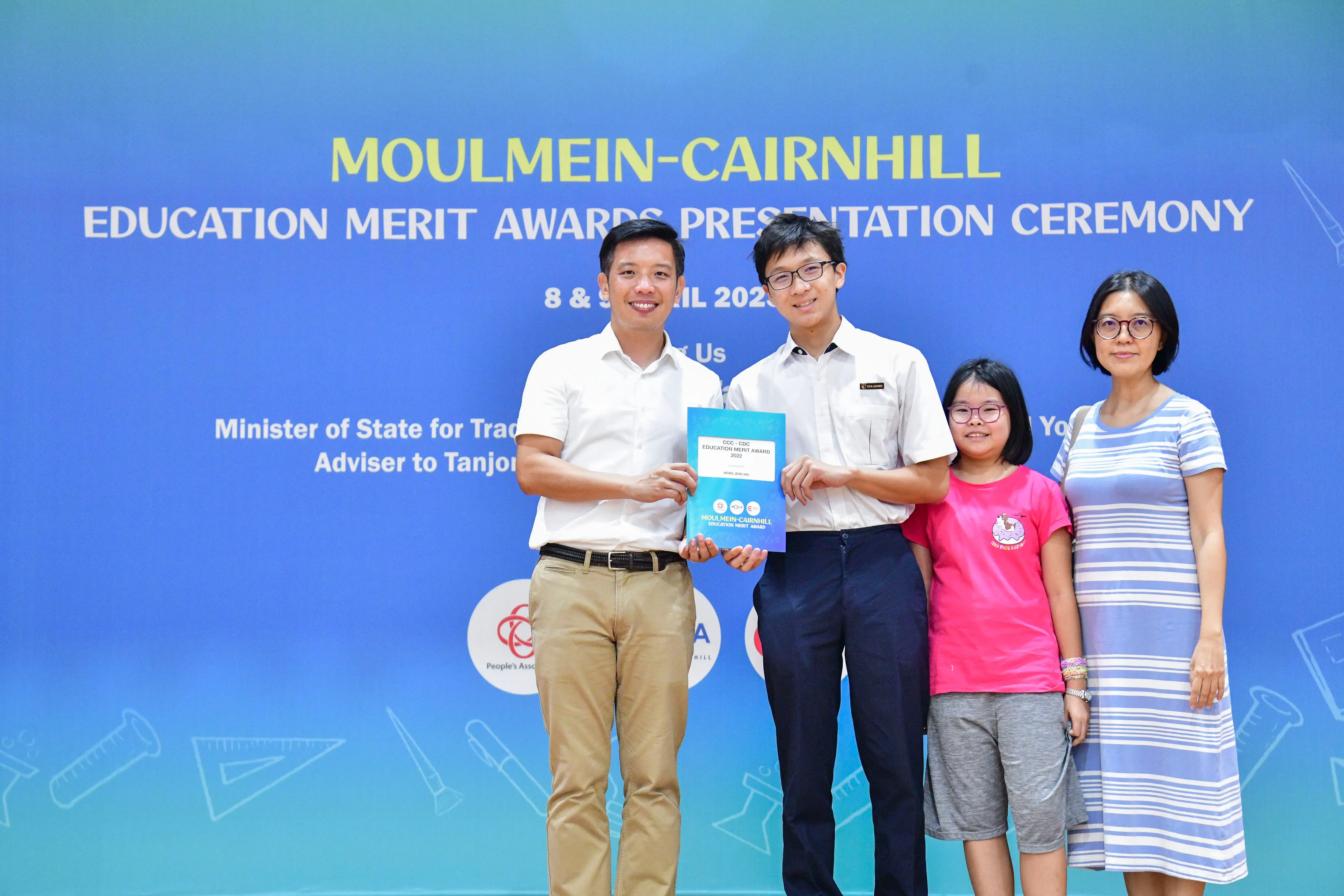 Four people pose holding a certificate at the Moulmein-Cairnhill Education Merit Awards Presentation Ceremony.