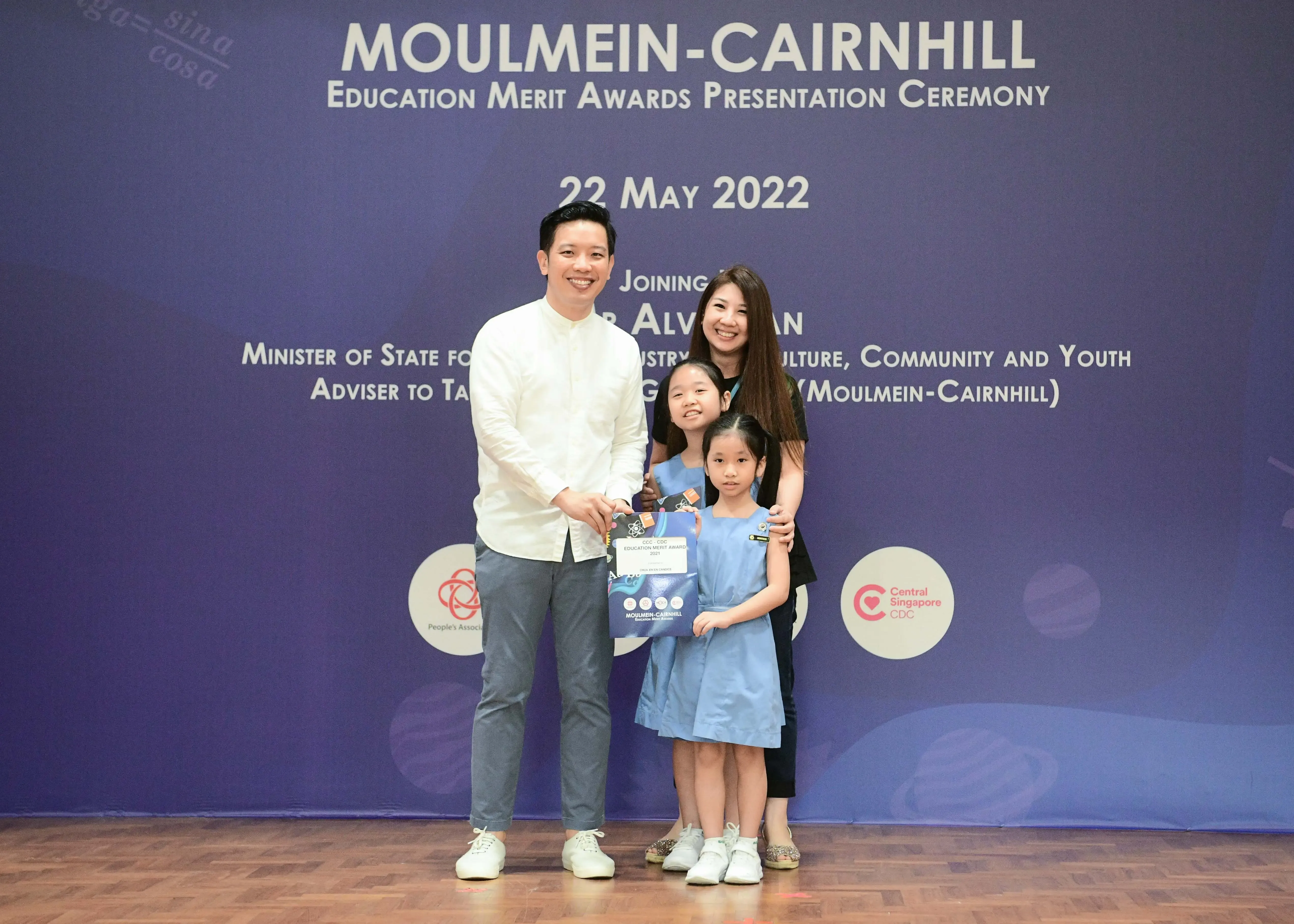 Two adults and two young girls pose at the Moulmein-Cairnhill Education Merit Awards Ceremony on 22 May 2022.