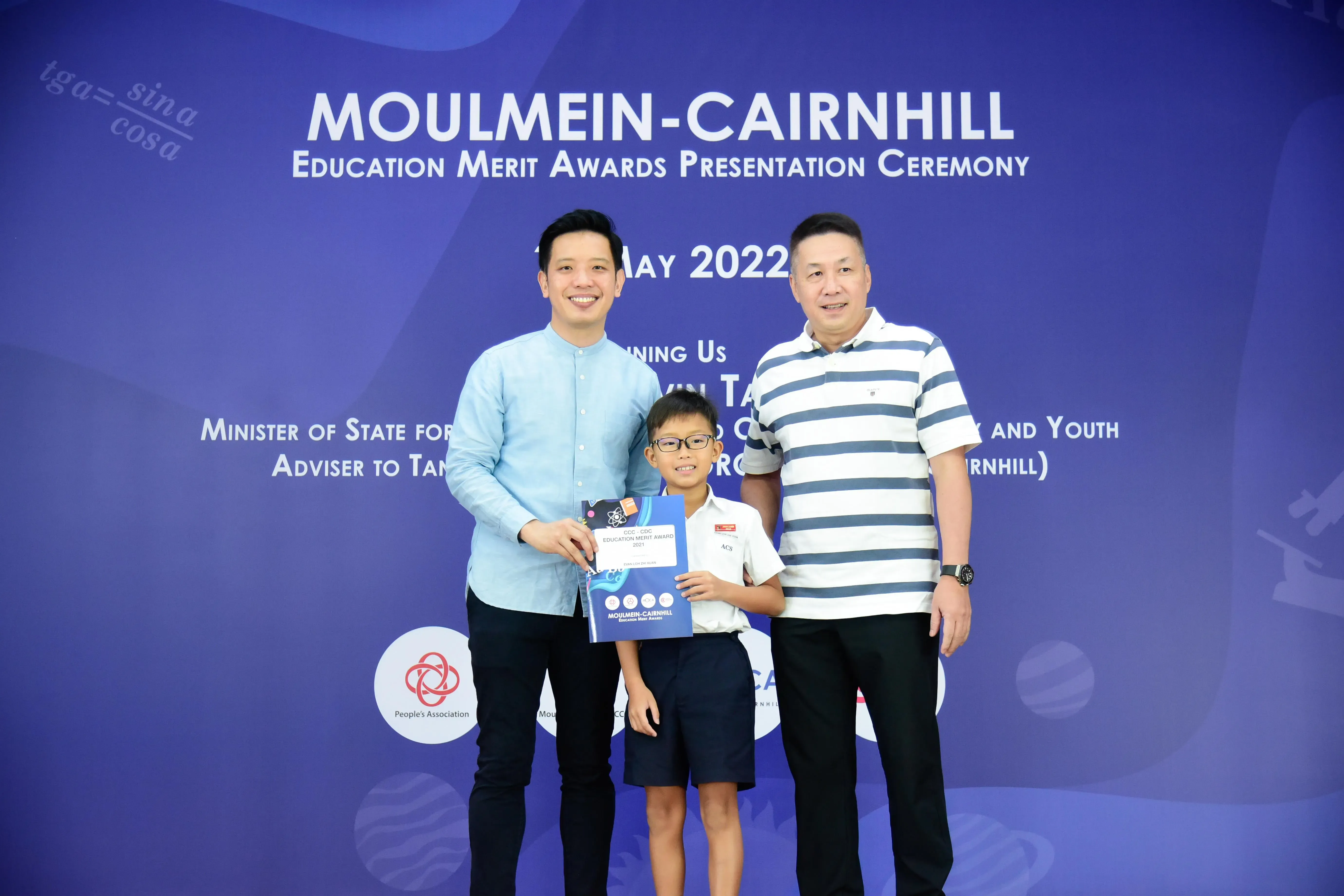 Two men and a young boy holding an award certificate at the Moulmein-Cairnhill Education Merit Awards May 2022.
