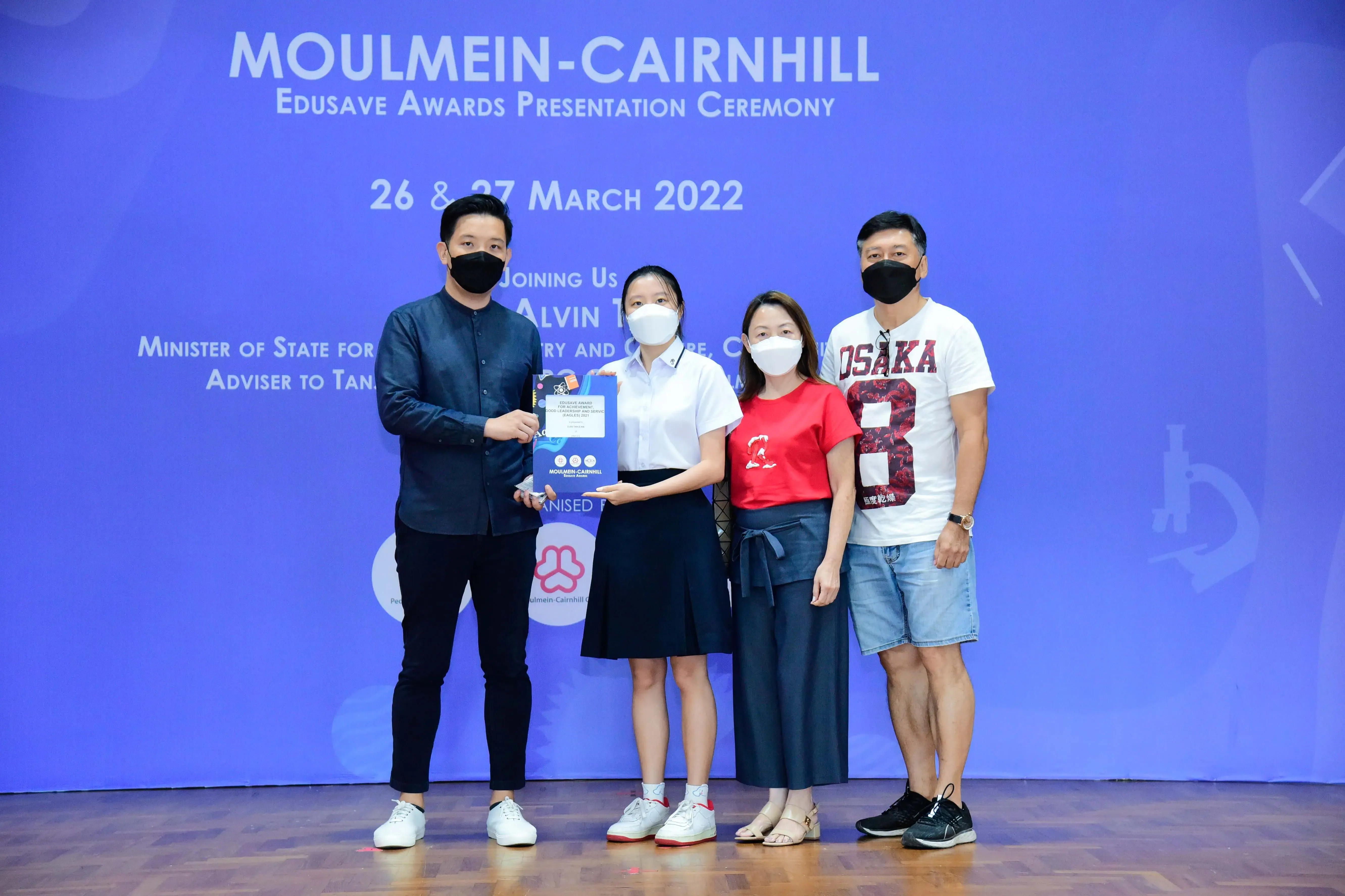 Four masked people pose at the Moulmein-Cairnhill Edusave Awards Presentation Ceremony on 26-27 March 2022.
