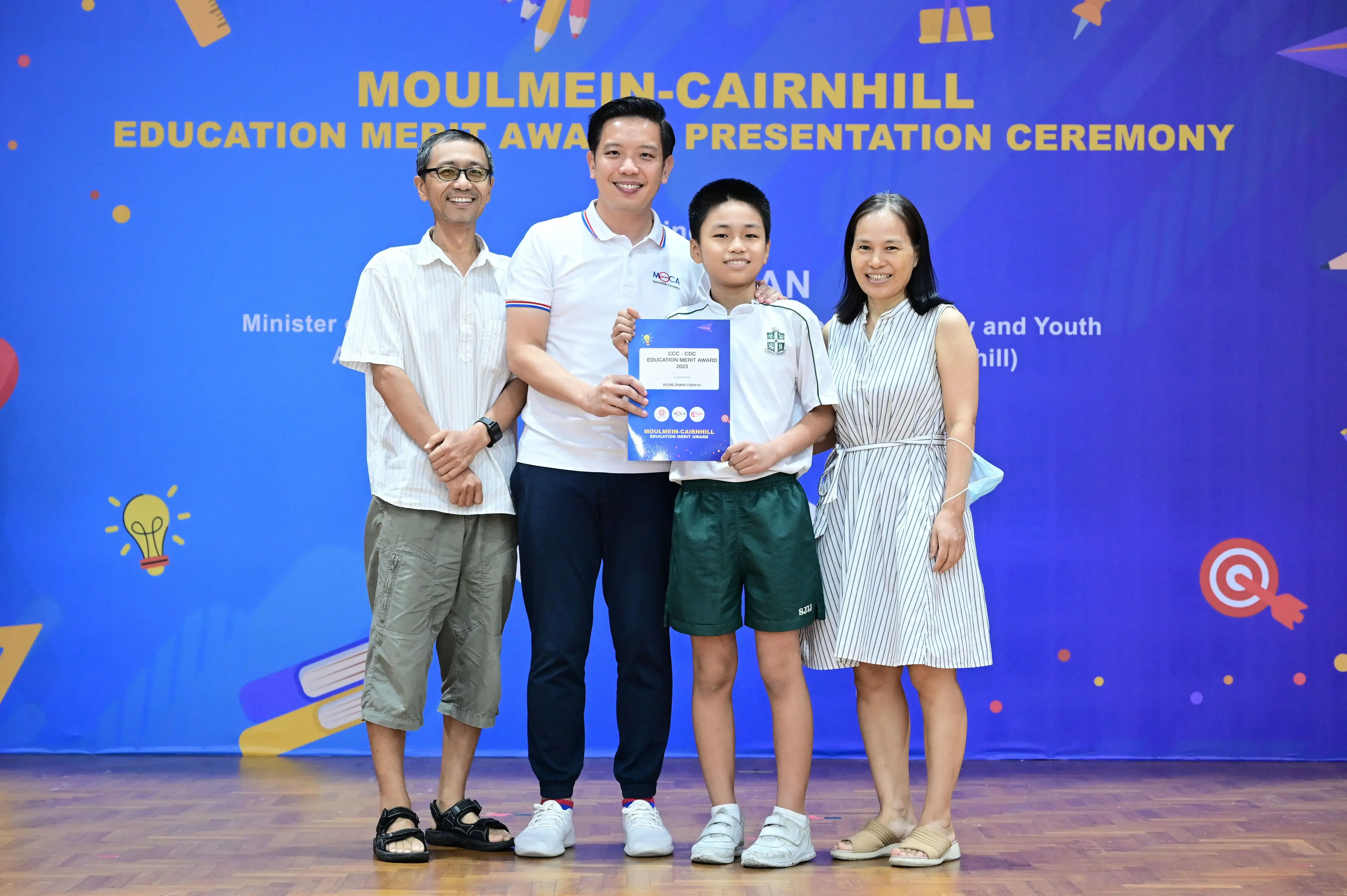 Four people pose with an award certificate at the Moulmein-Cairnhill Education Merit Award Presentation Ceremony.